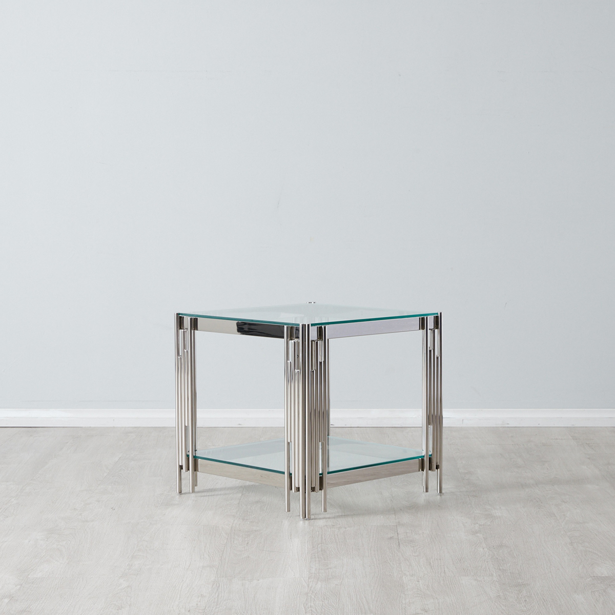 Mesa de apoio quadrada em vidro e metal sobre chão claro