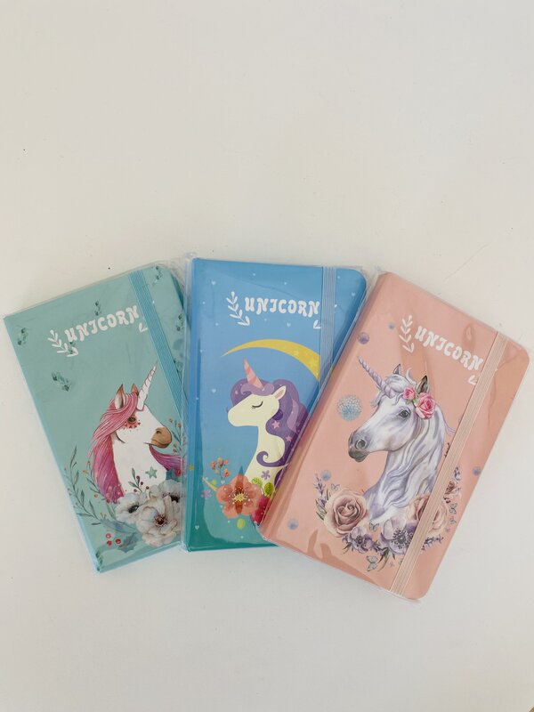 Três cadernos coloridos com ilustrações de unicórnios e a palavra UNICORN