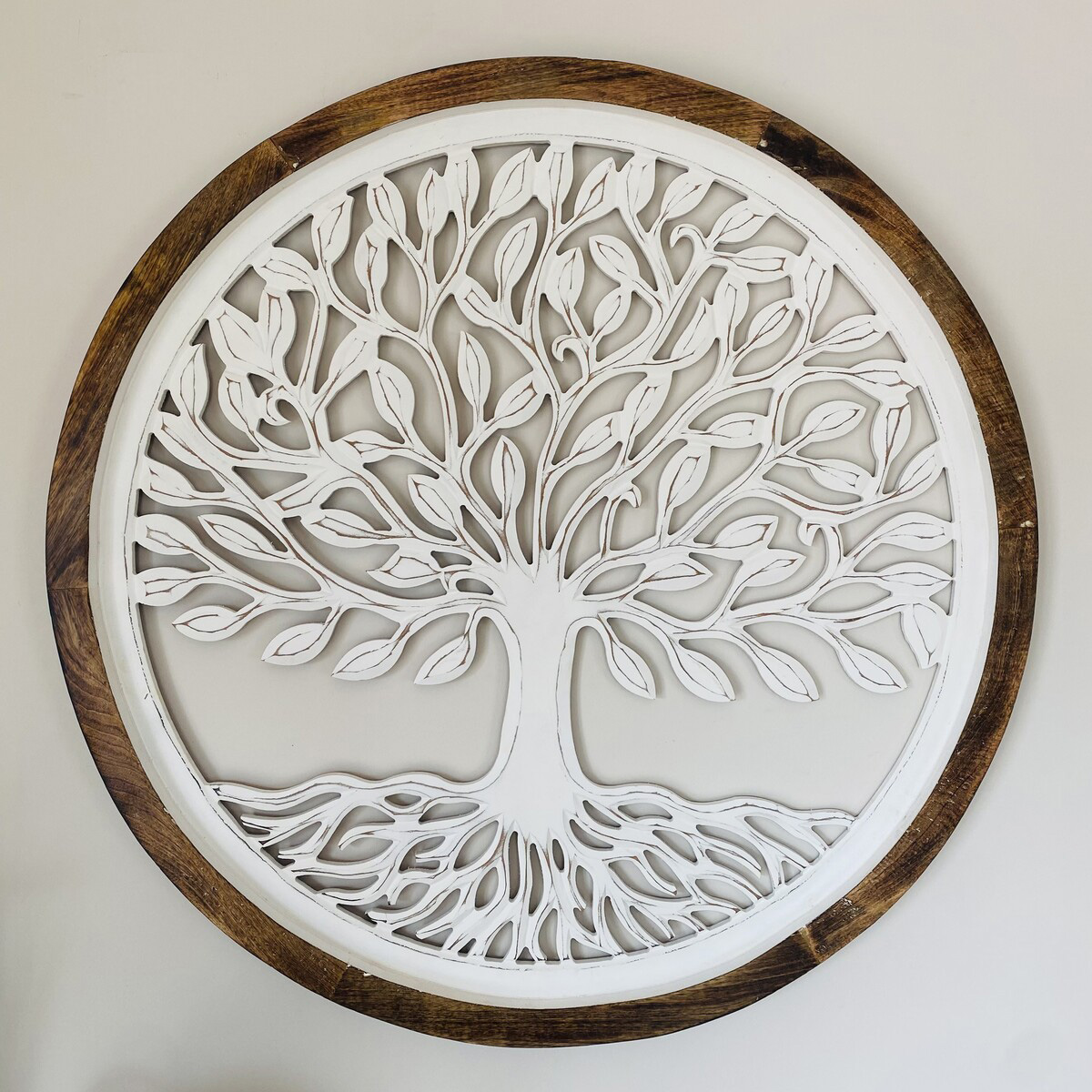 Relógio de parede redondo de madeira com desenho de árvore branca no interior.
