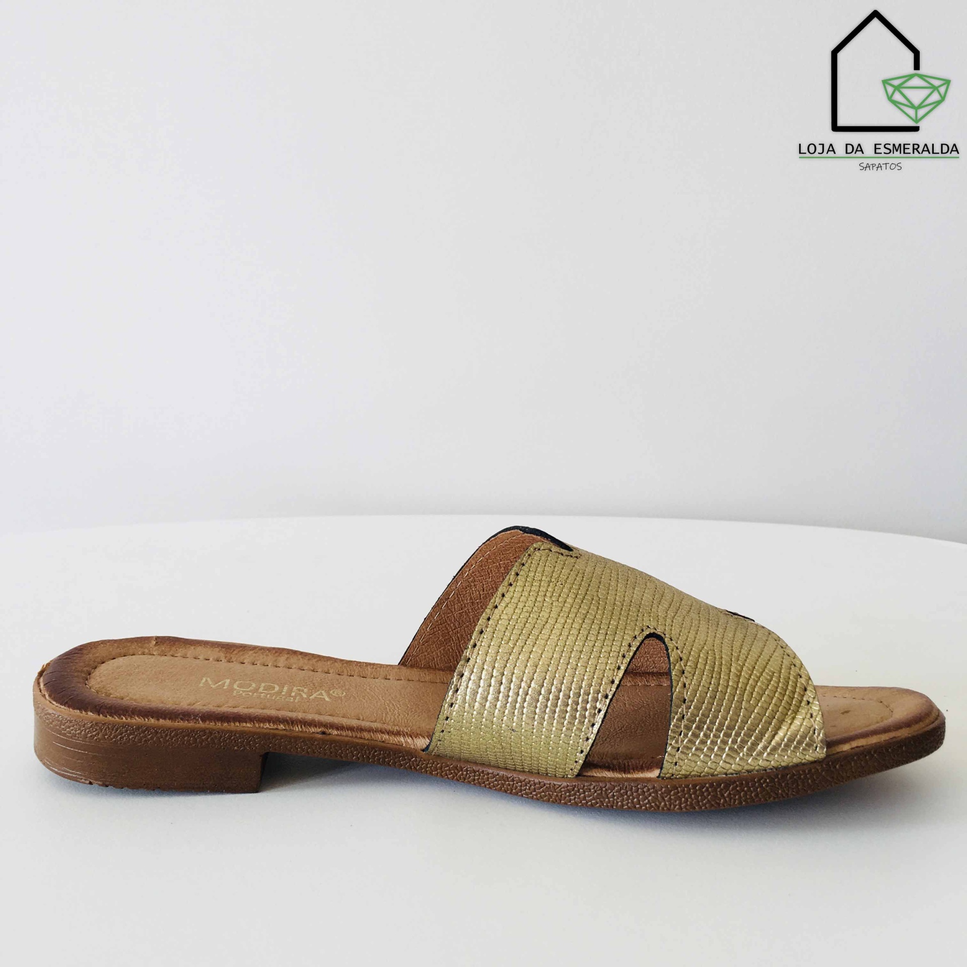 Sandália rasteira dourada e castanha com sola escura e textura riscada