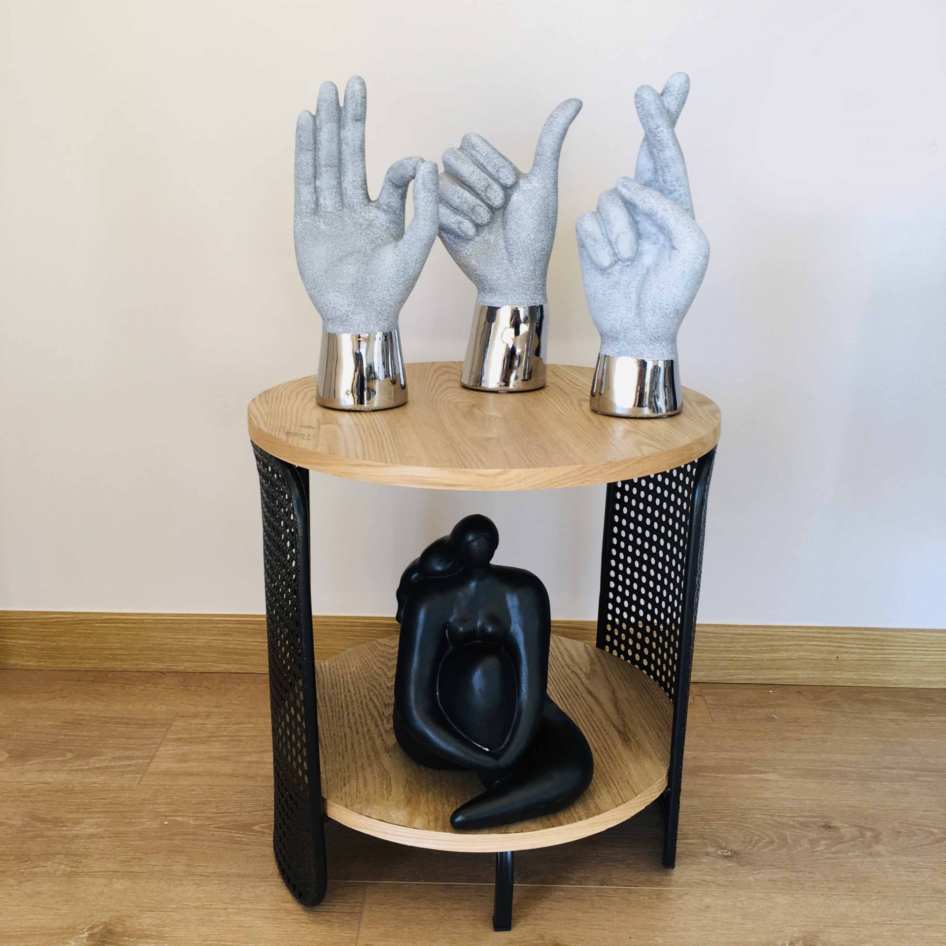 Mesa redonda de madeira com esculturas decorativas de mãos cinza e escultura preta abstrata