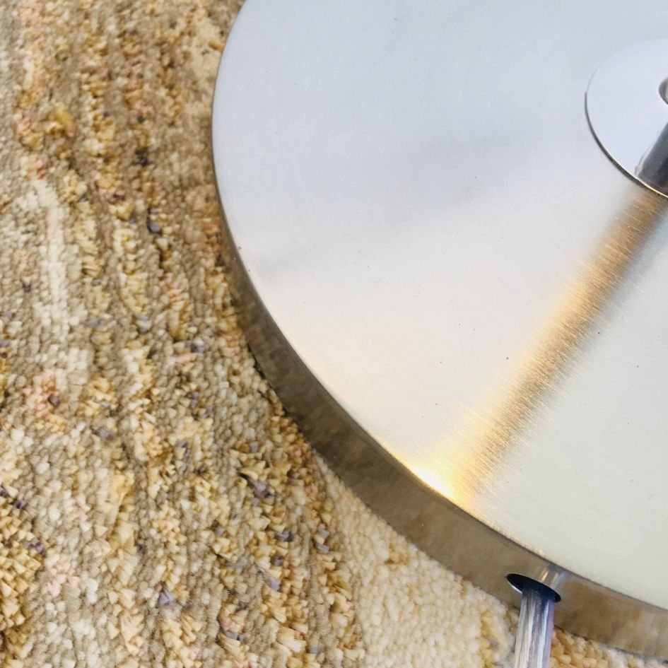 Base metálica prateada sobre superfície têxtil bege