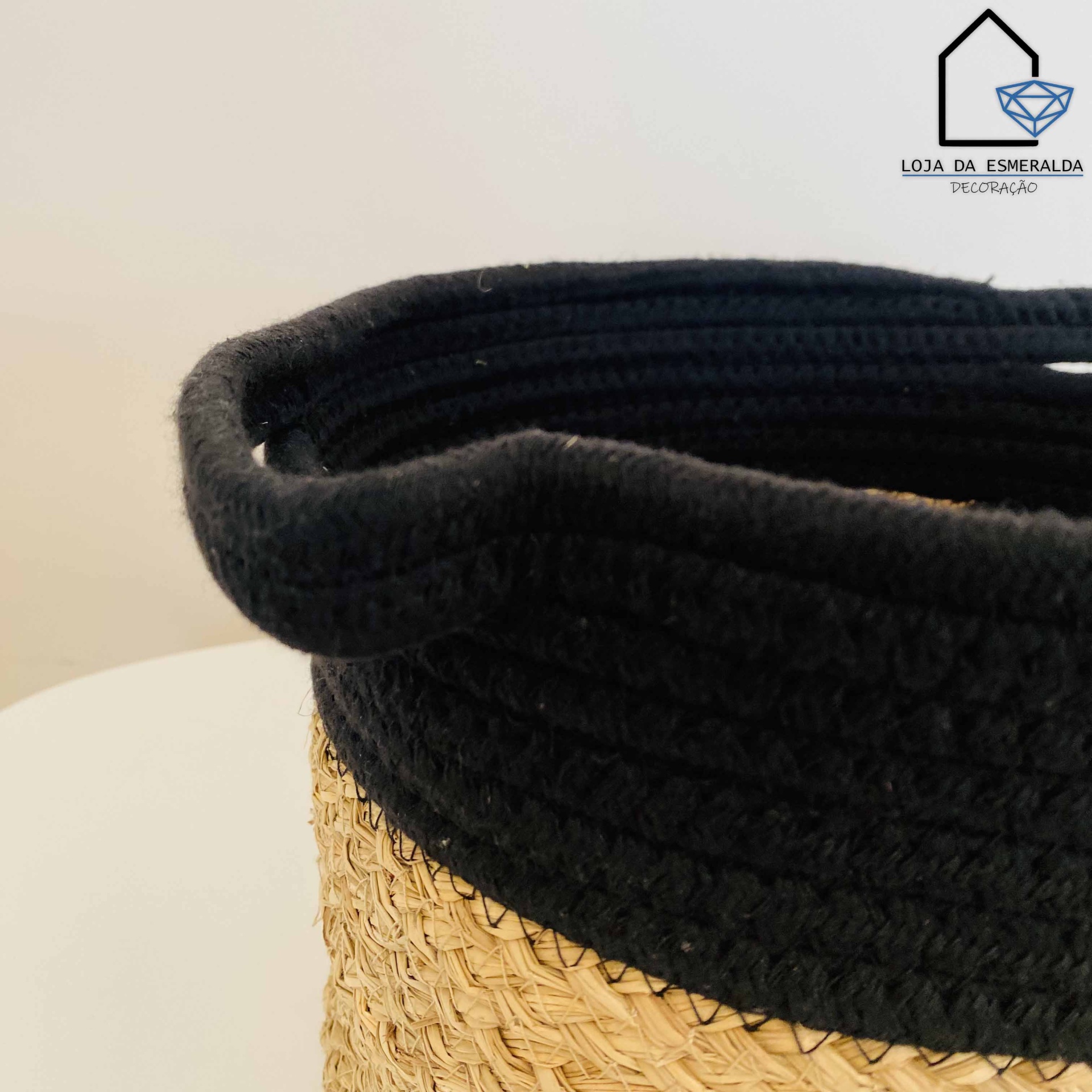 Cesto decorativo em fibras naturais com borda preta e alça, em fundo branco