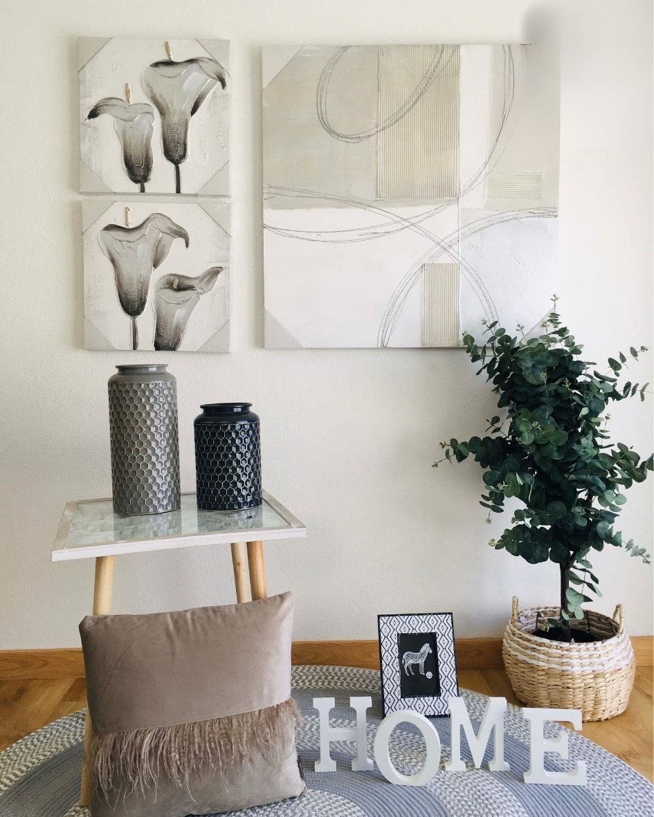 Vasos decorativos cinza e preto, almofada bege, letras HOME, moldura com zebra e planta em cesto de vime