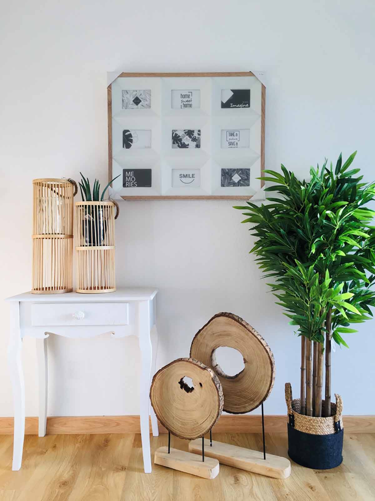 Mesa branca com castiçais de madeira, plantas e ornamentos de madeira junto a planta alta em vaso preto