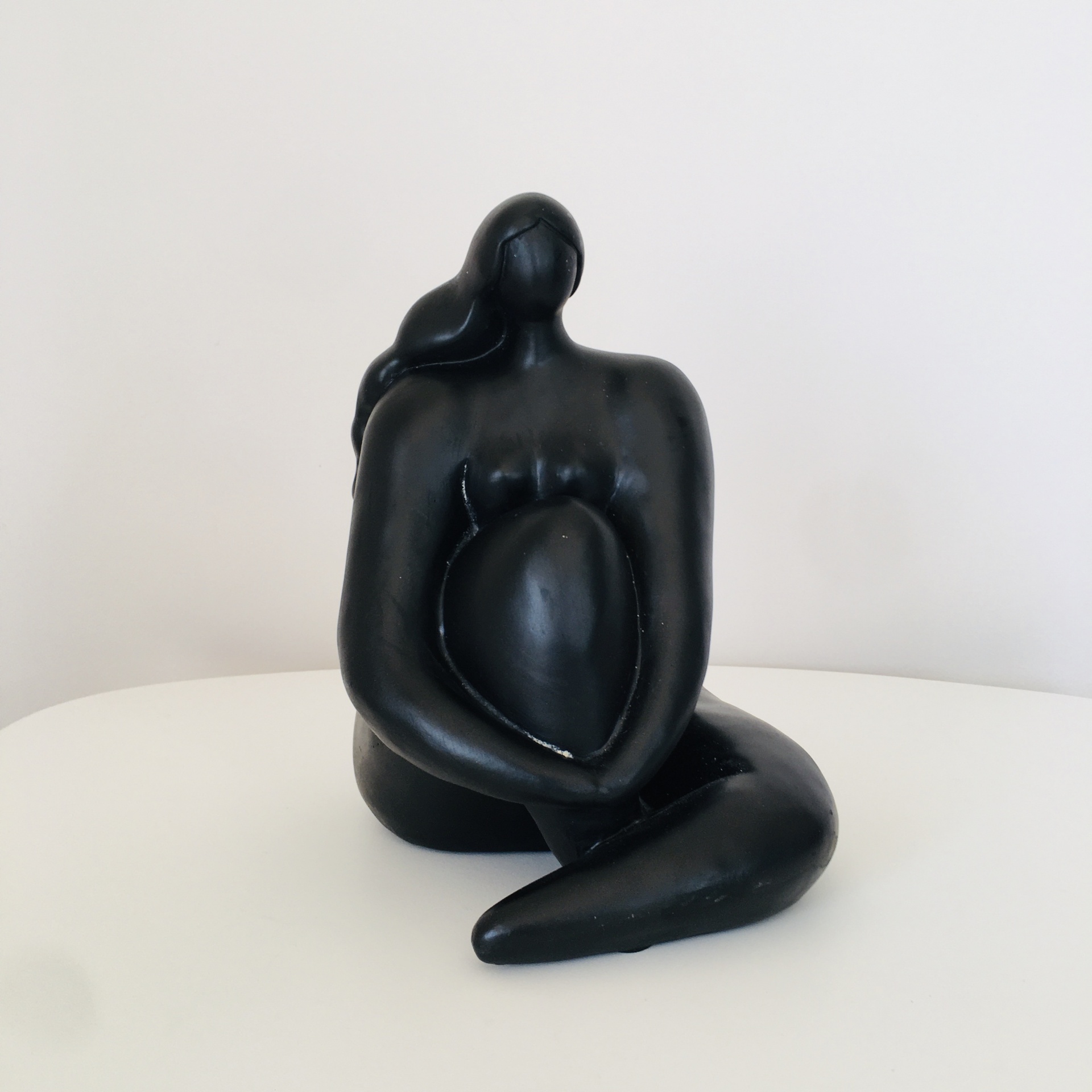 Escultura decorativa preta de figura humana sentada