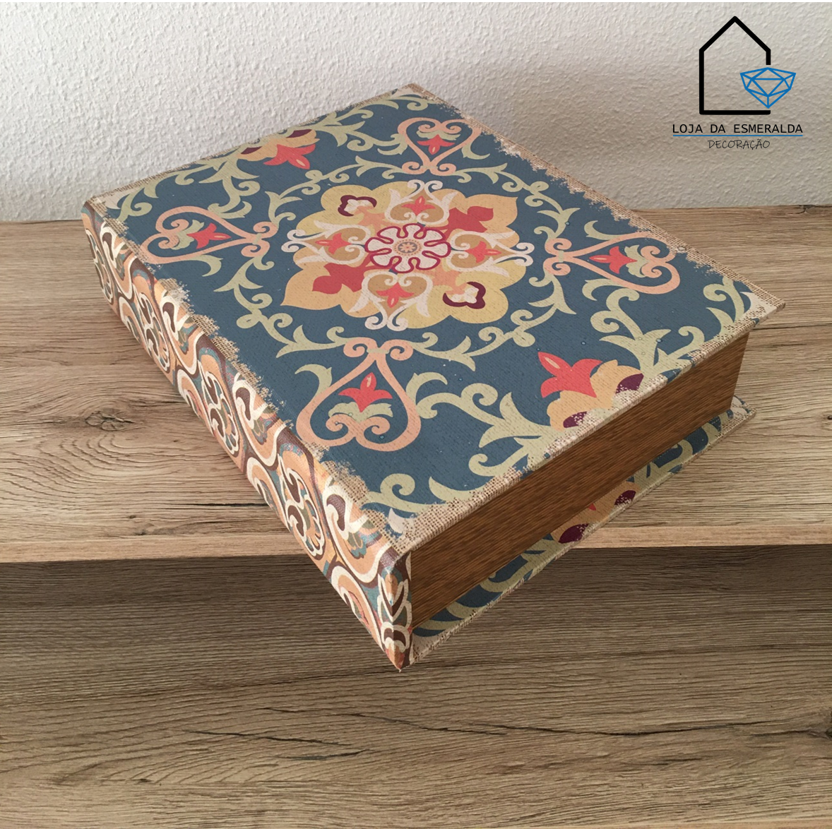 Livro com capa floral azul, vermelho e bege sobre superfície de madeira clara