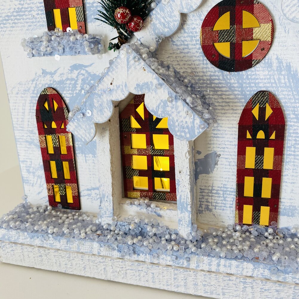 Casa decorativa de madeira com detalhes coloridos e neve artificial