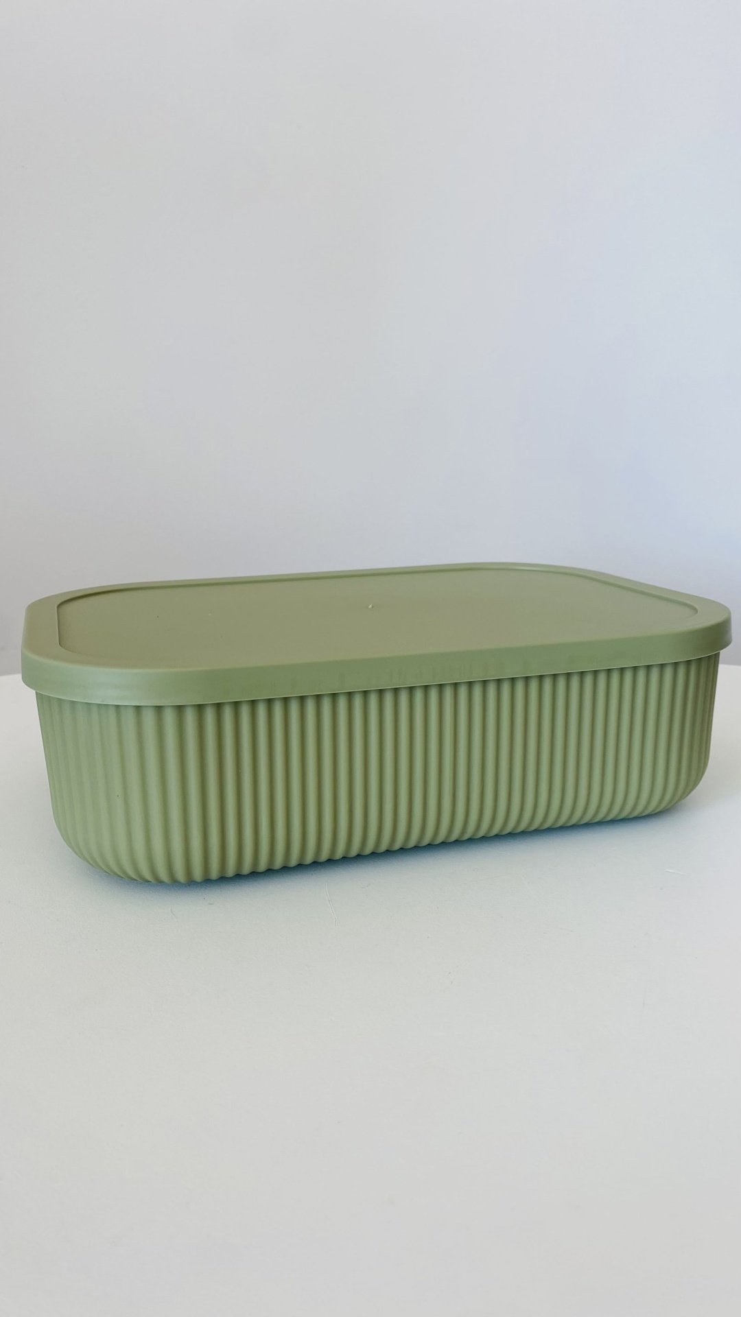 Caixa plástica verde claro com tampa e textura estriada nas laterais