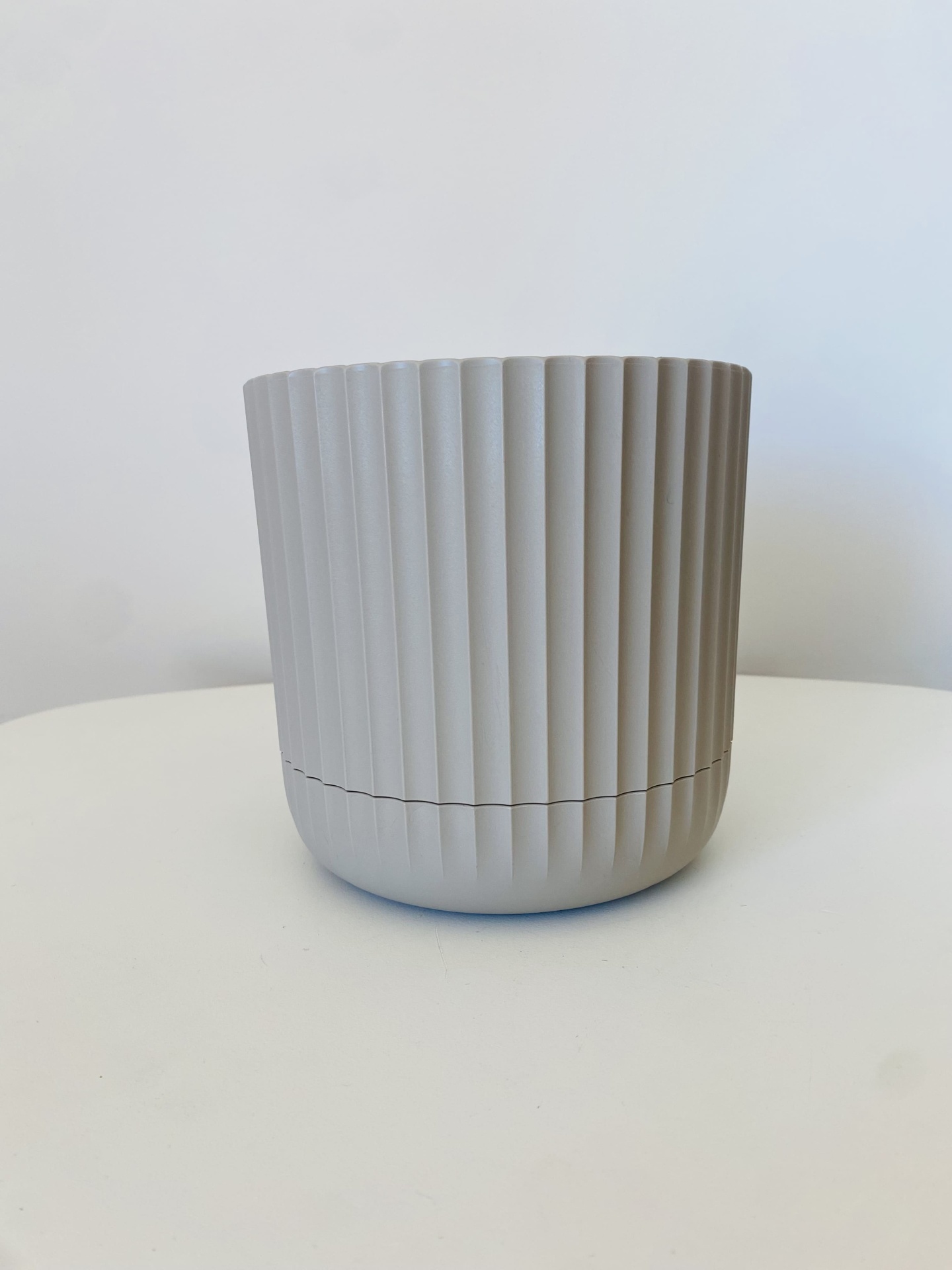 Vaso cinzento claro com linhas verticais sobre superfície branca