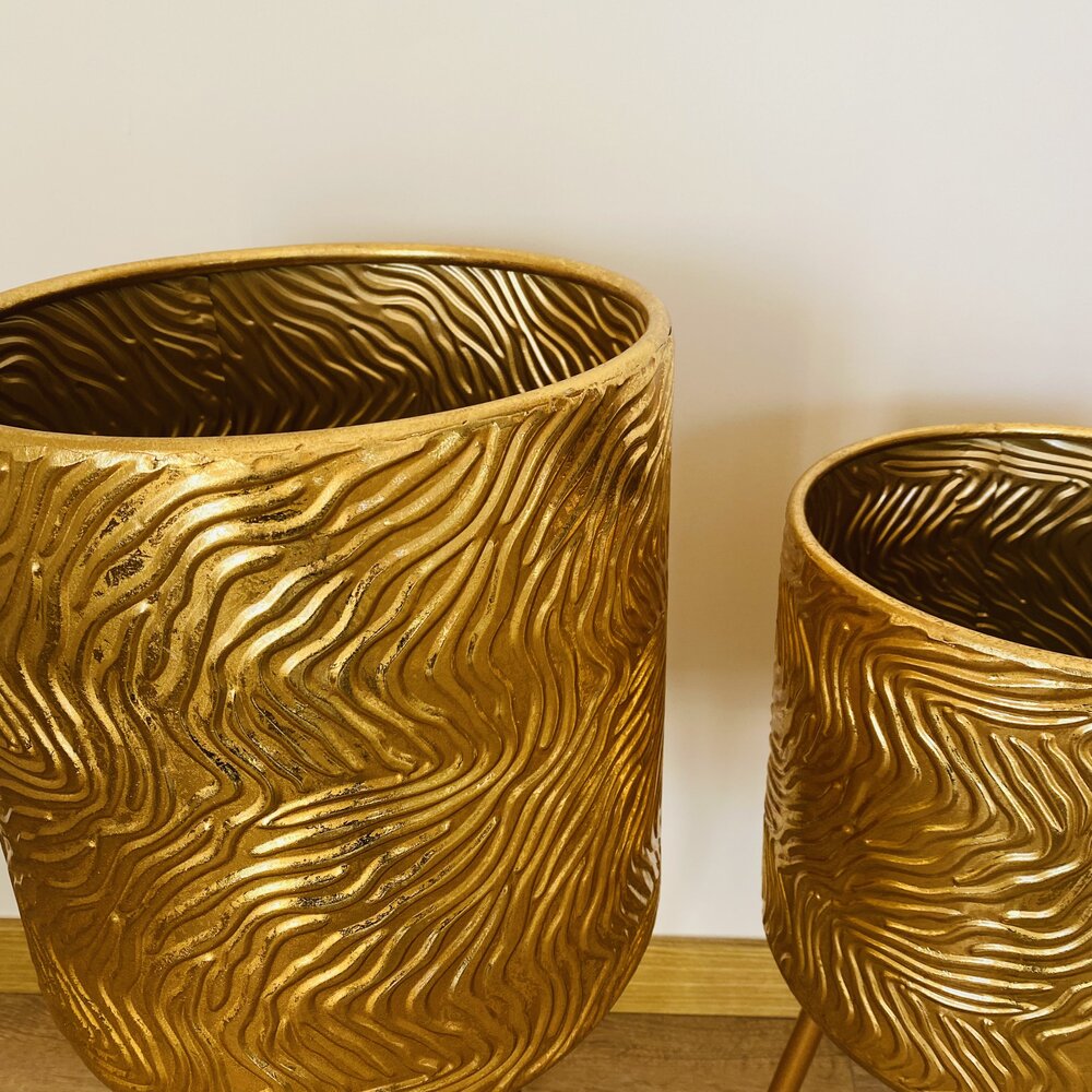Dois vasos dourados com textura ondulada sobre superfície de madeira