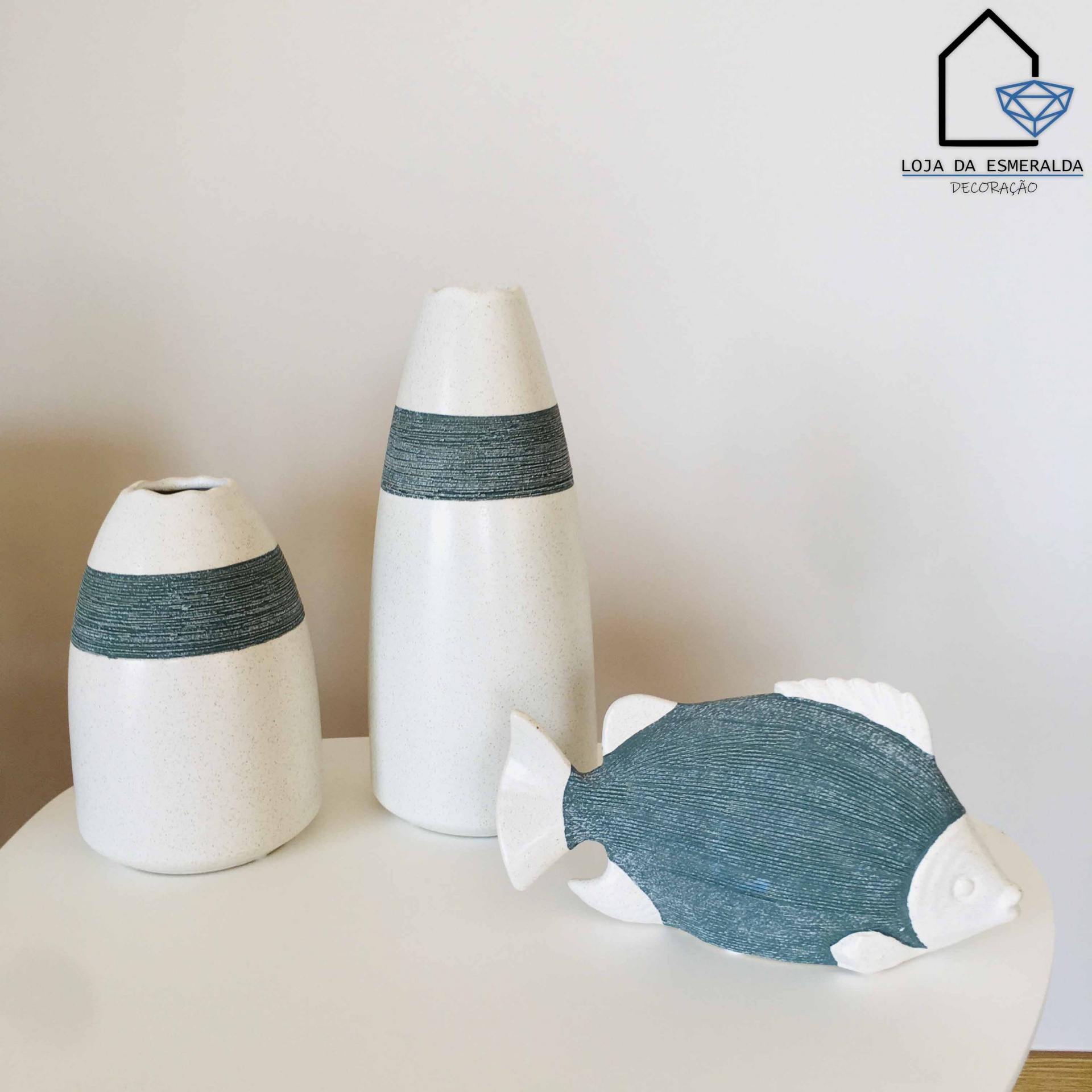 Três peças decorativas em cerâmica branca e azul numa mesa branca