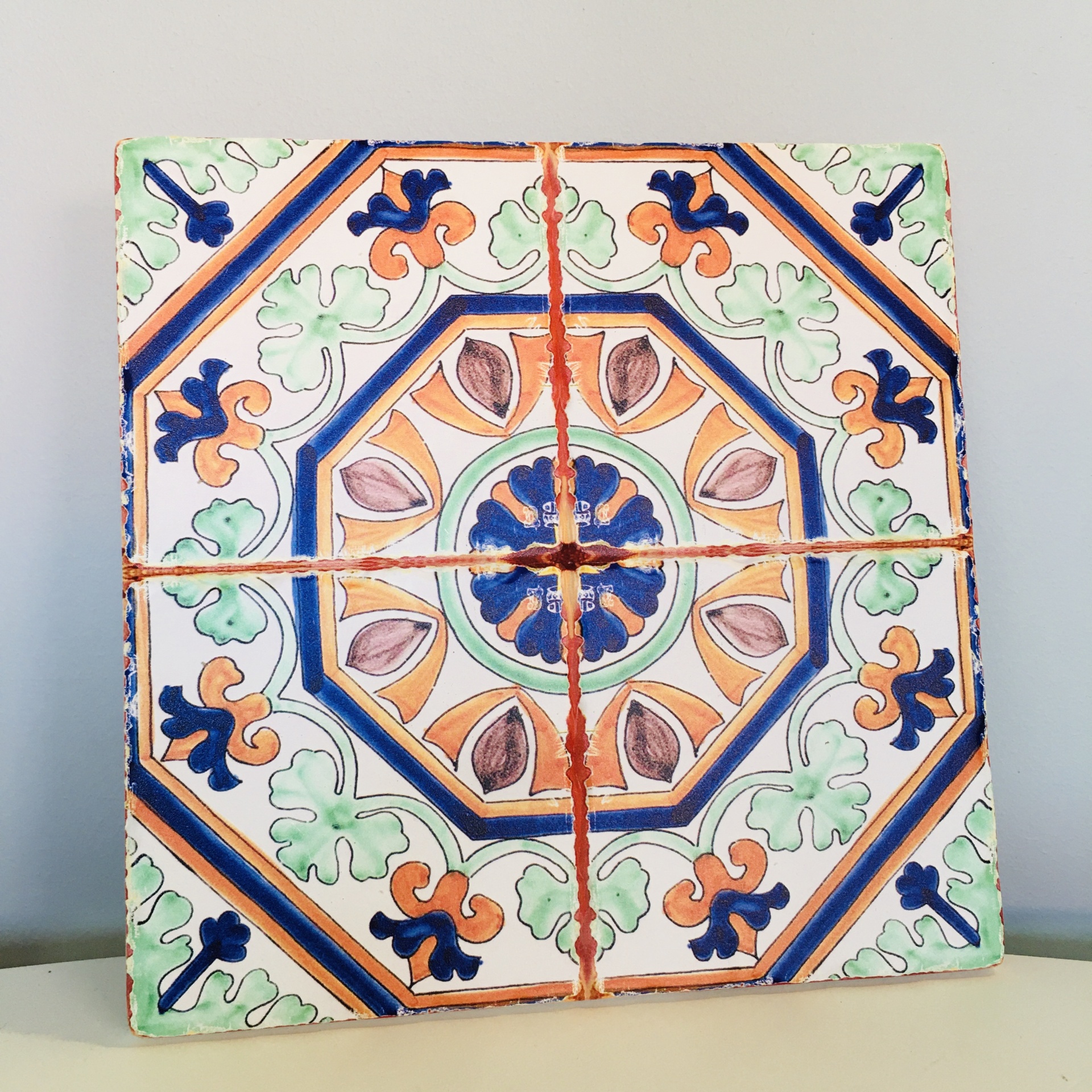 Conjunto de quatro azulejos cerâmicos decorativos coloridos com padrão floral simétrico.