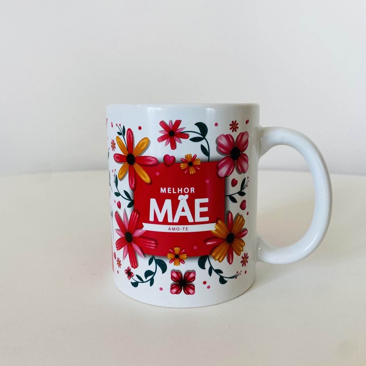 Caneca branca com flores vermelhas e amarelas e texto 