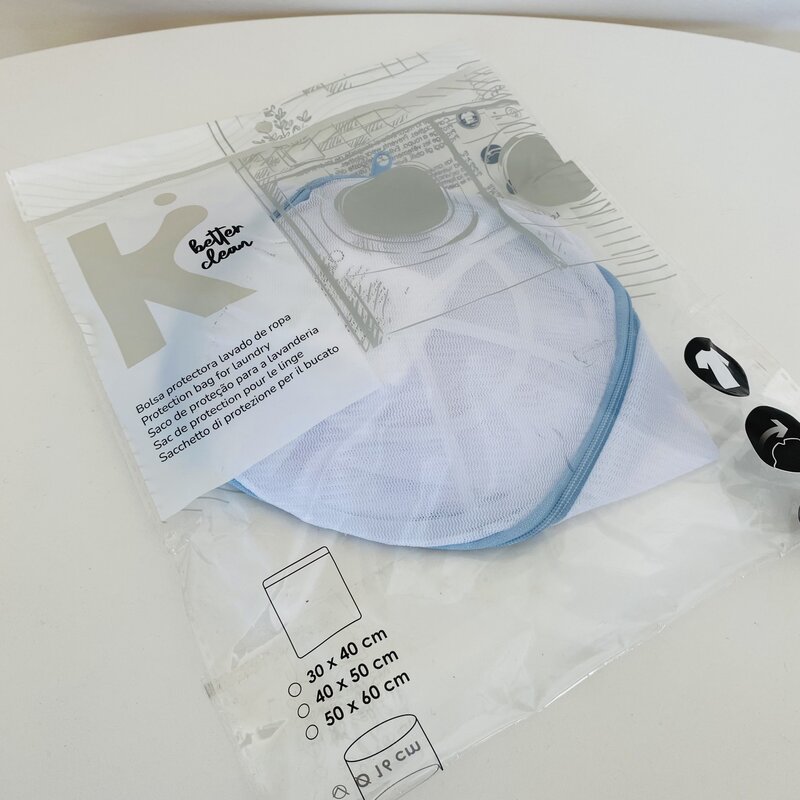 Saco protetor de roupa branco com borda azul em embalagem de plástico transparente