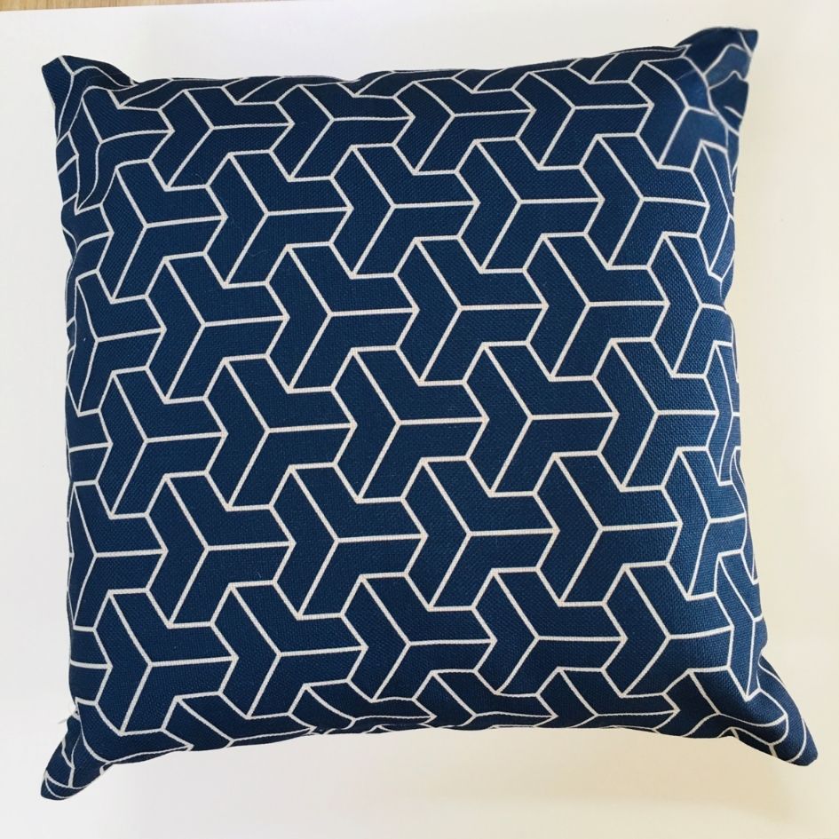 almofada azul escuro com padrão geométrico branco