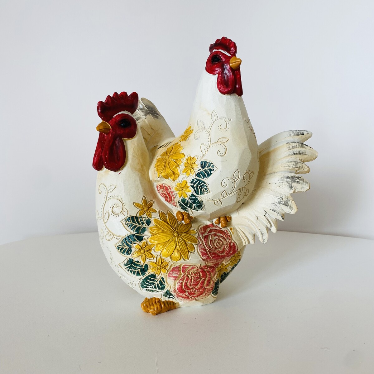 Figura decorativa de duas galinhas em cerâmica com flores coloridas