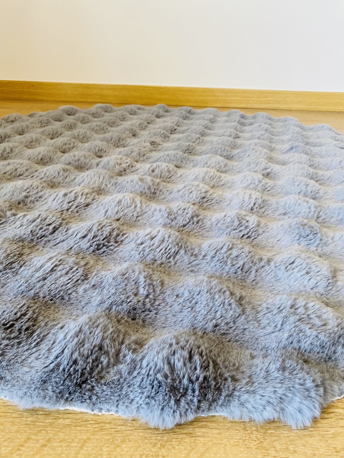 Tapete cinzento macio com textura ondulada em chão de madeira