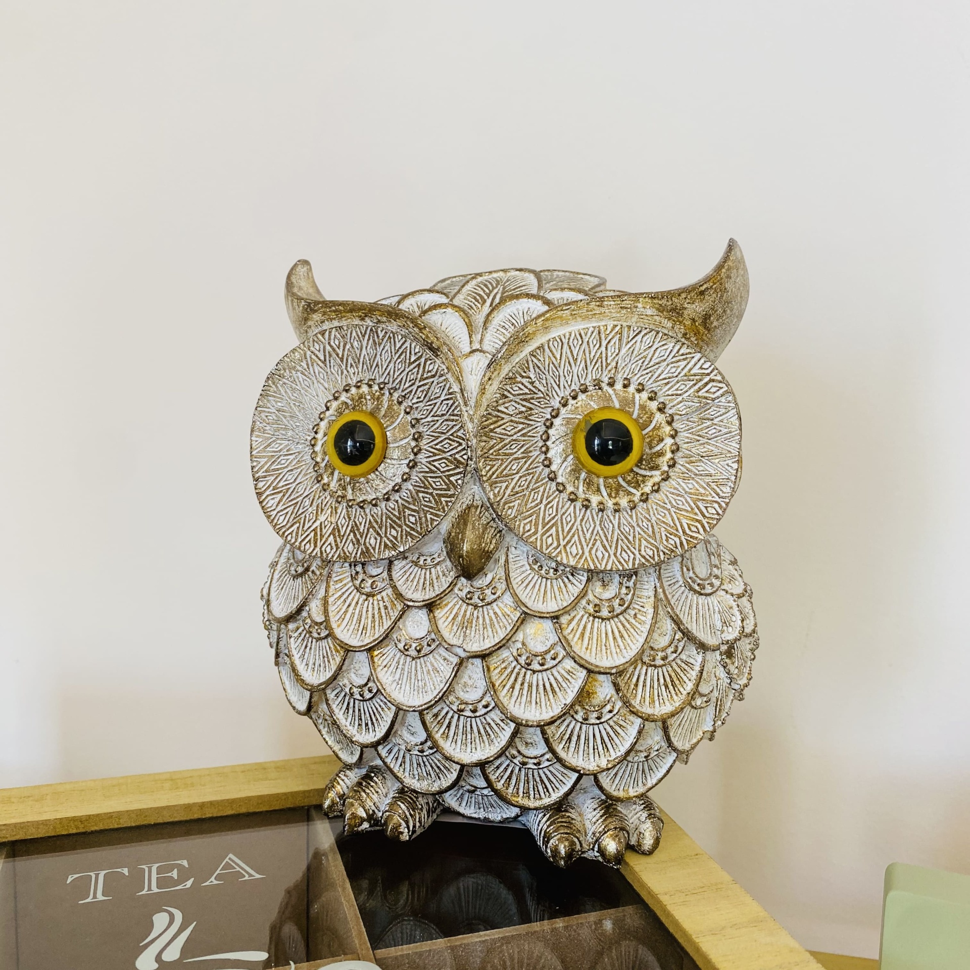 Figura decorativa de coruja em cerâmica ou resina com textura detalhada e olhos amarelos