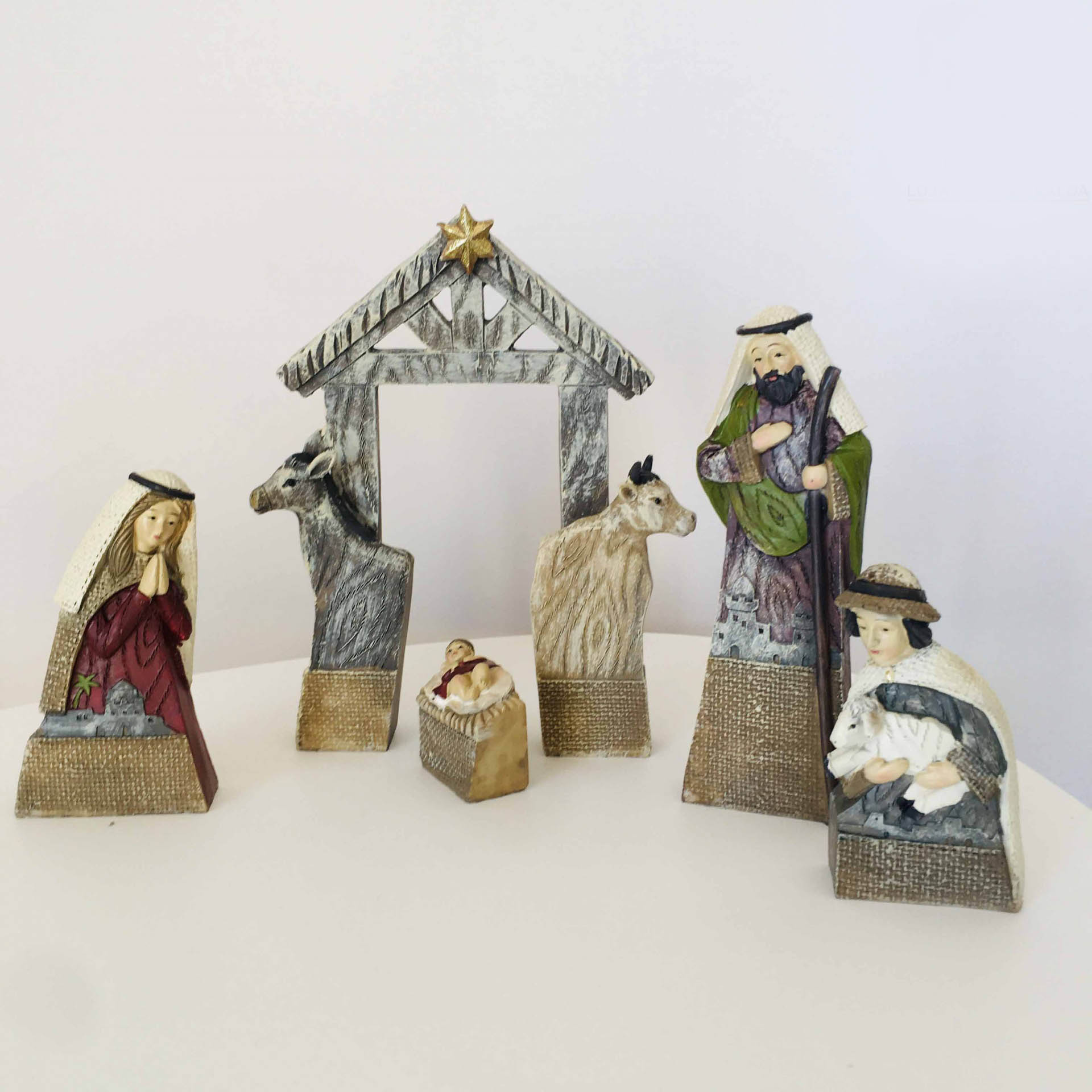 Conjunto de figuras de presépio em madeira pintada com base texturizada.