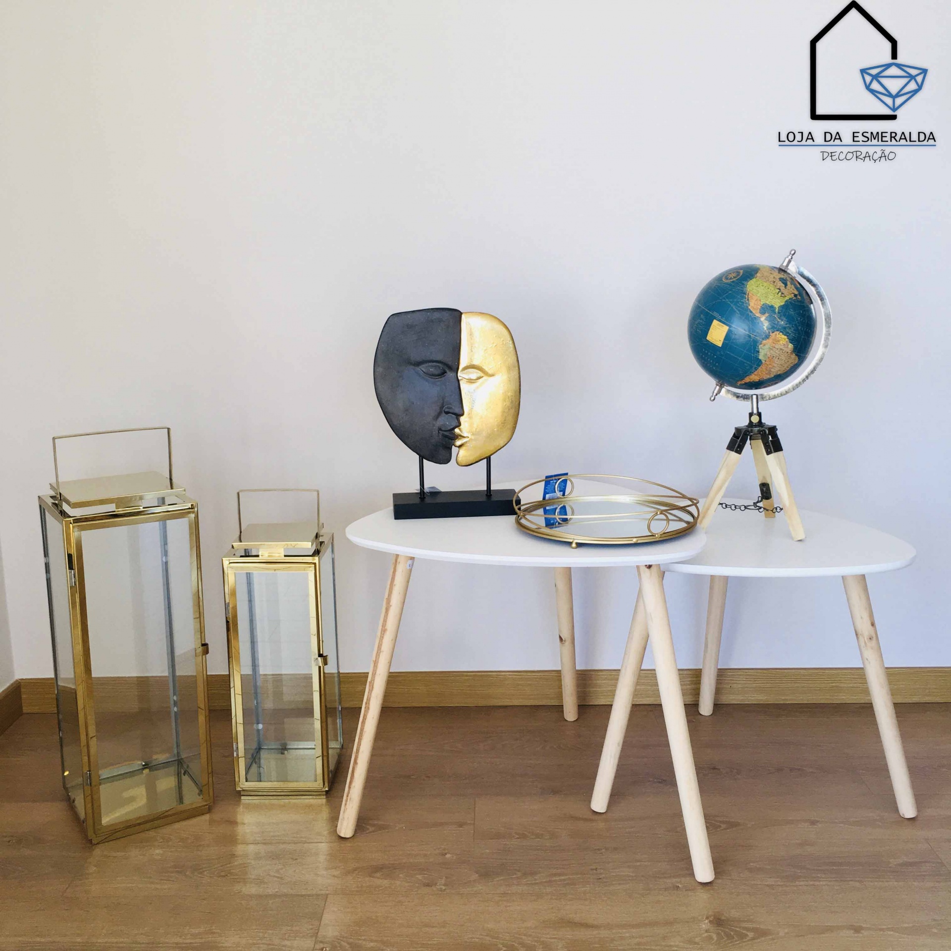 mesa branca com decoração incluindo máscara metade preta metade dourada, bandeja dourada e globo terrestre