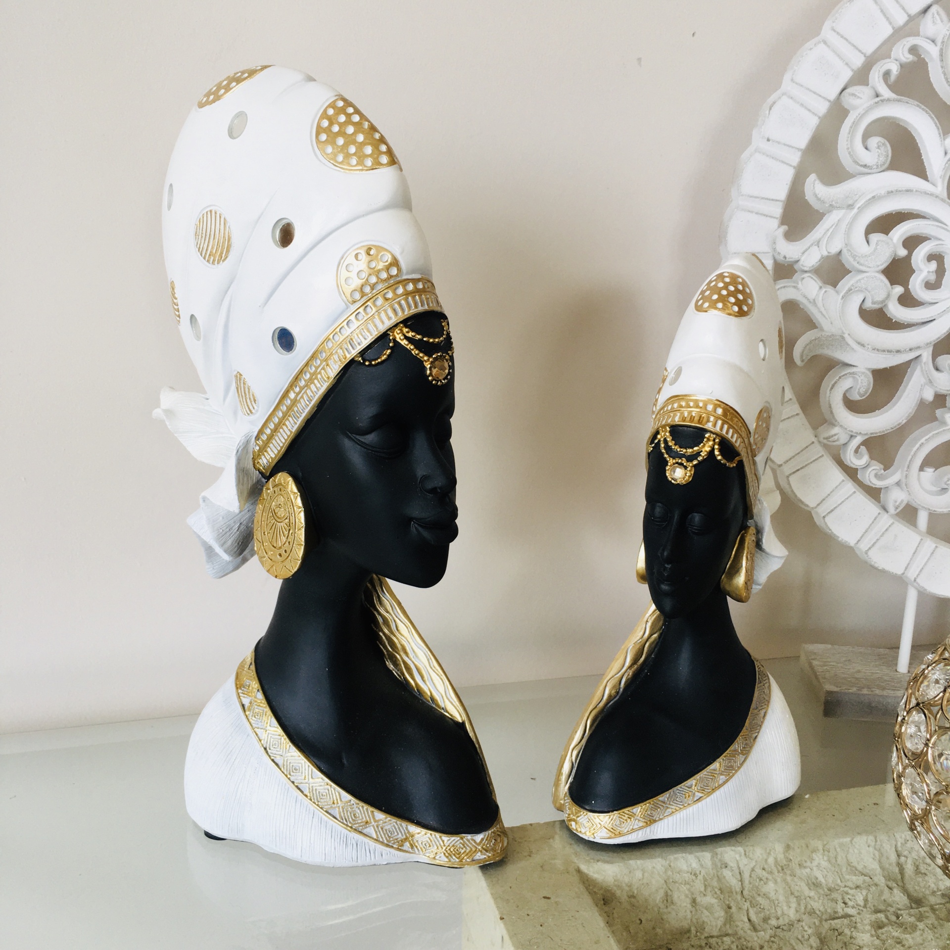 Dois bustos decorativos femininos em preto com detalhes dourados e turbantes brancos