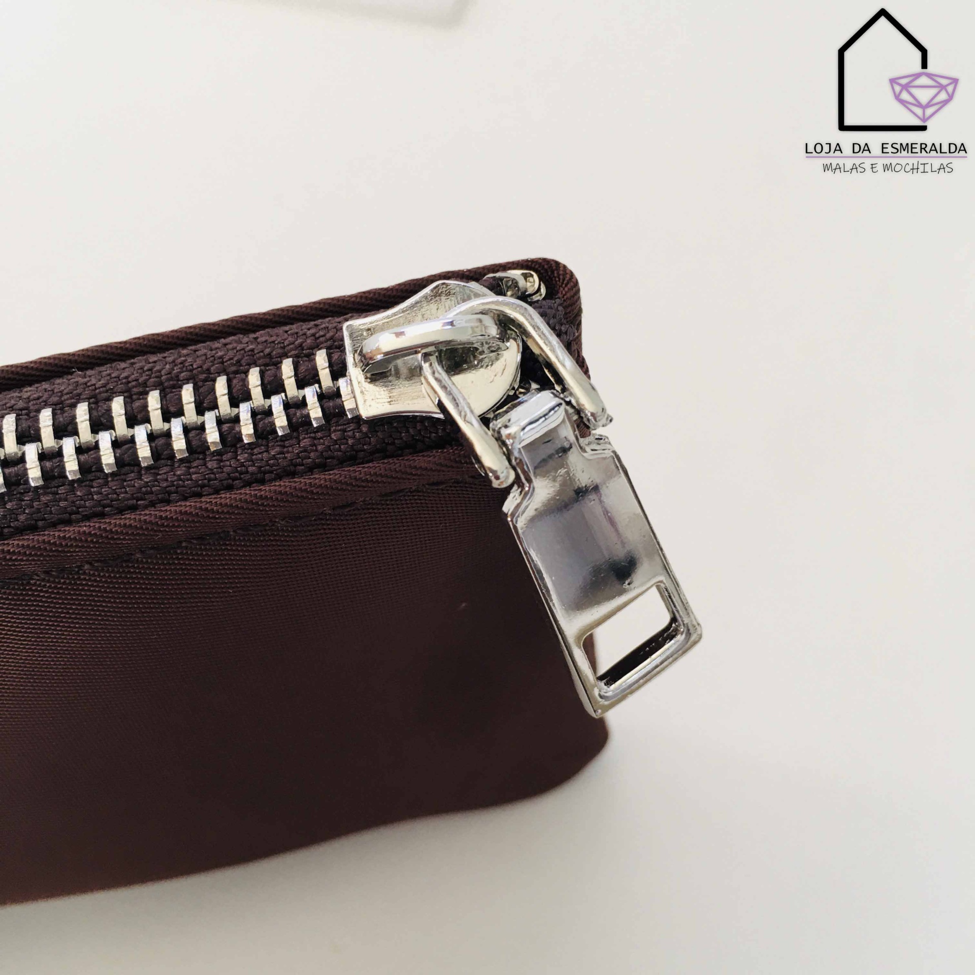 Fecho de zíper metálico prateado em bolsa castanha escura com logotipo