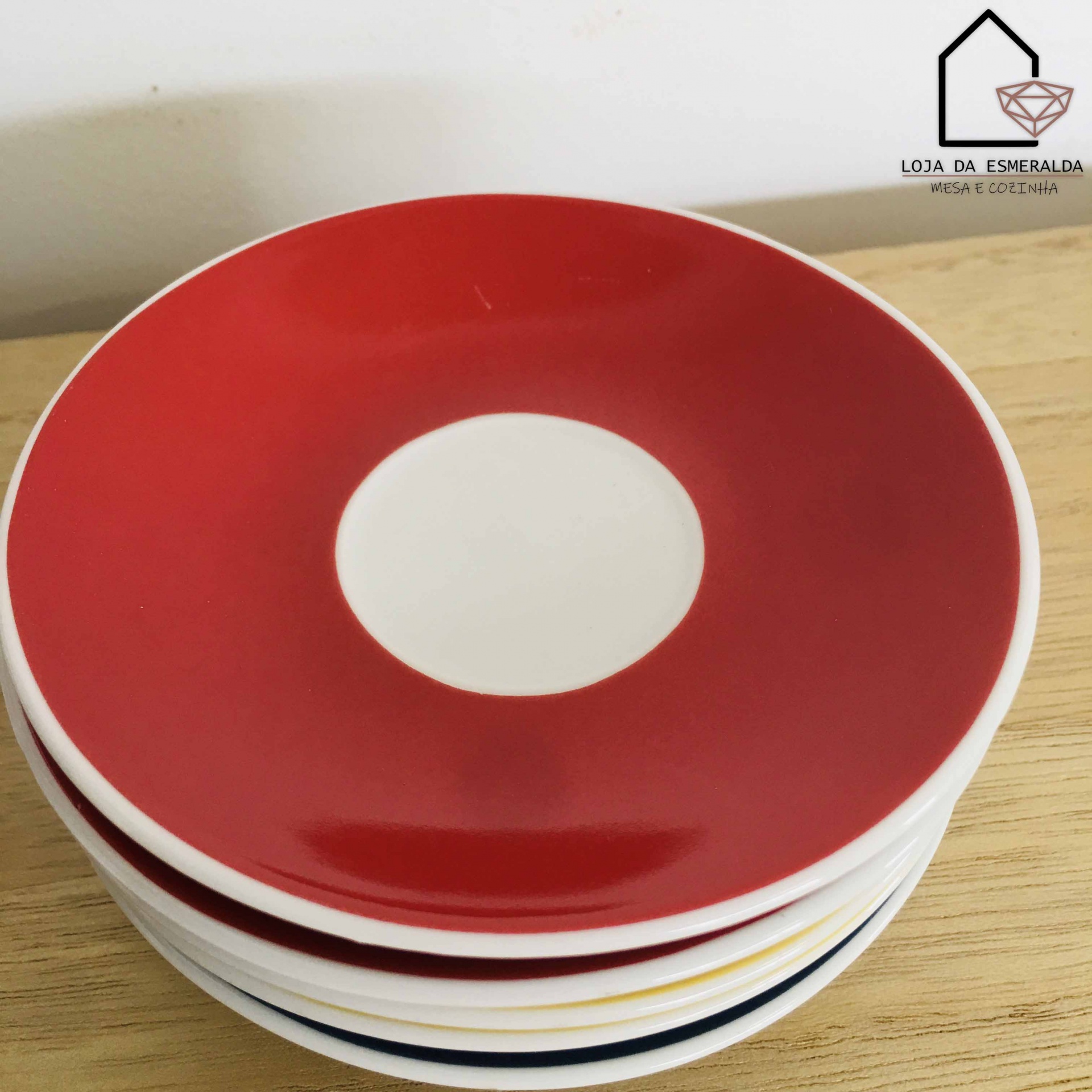 Conjunto de pratos cerâmicos empilhados, prato superior vermelho com centro branco, superfície de madeira
