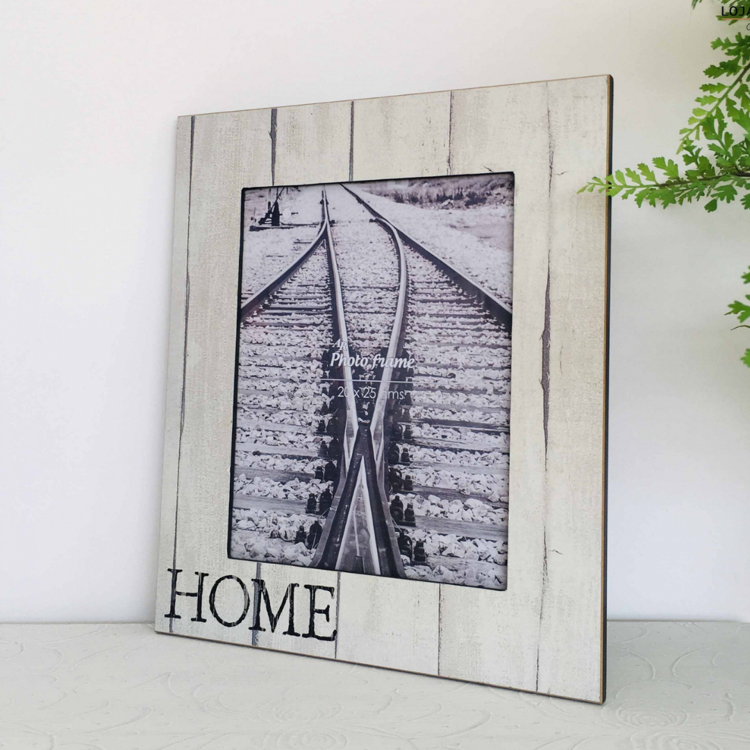Moldura de foto branca envelhecida com palavra HOME e fotografia de linha de comboio