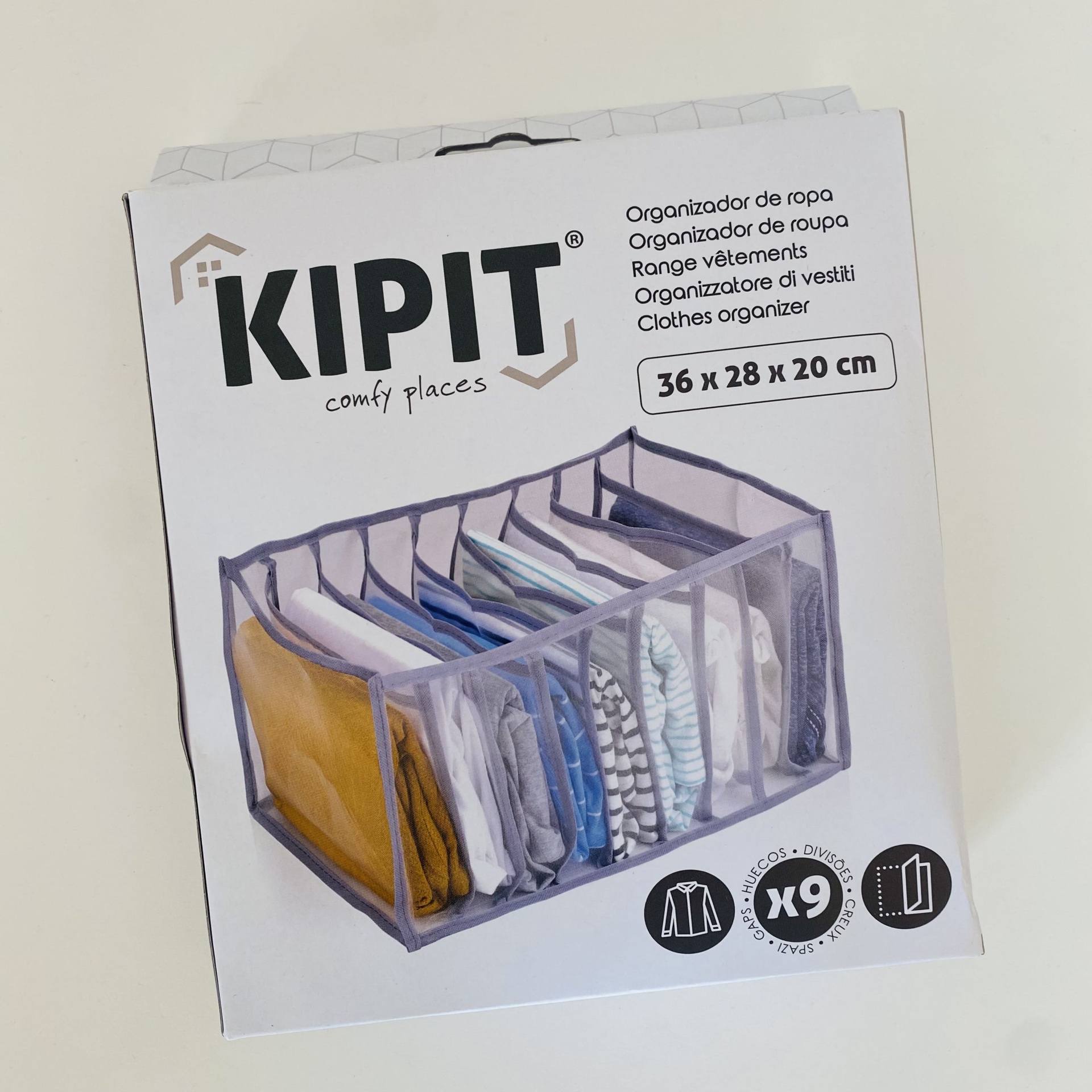 Caixa organizadora de roupa cinza da marca KIPIT com roupas dentro, em caixa branca de papel