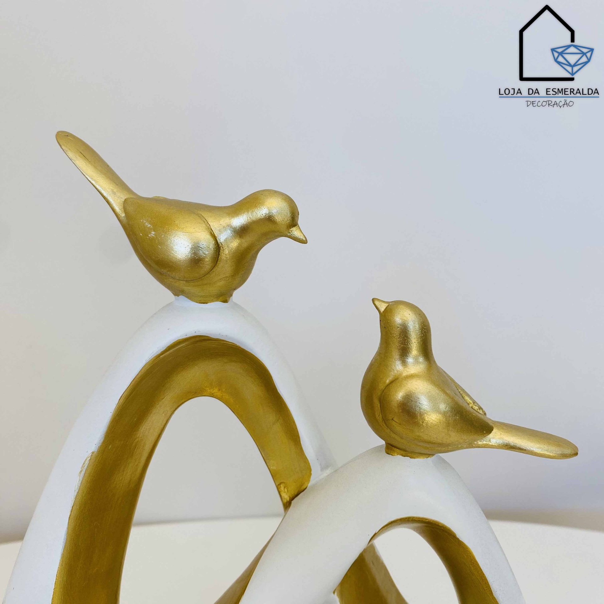 Esculturas decorativas de pássaros dourados em arcos brancos e dourados