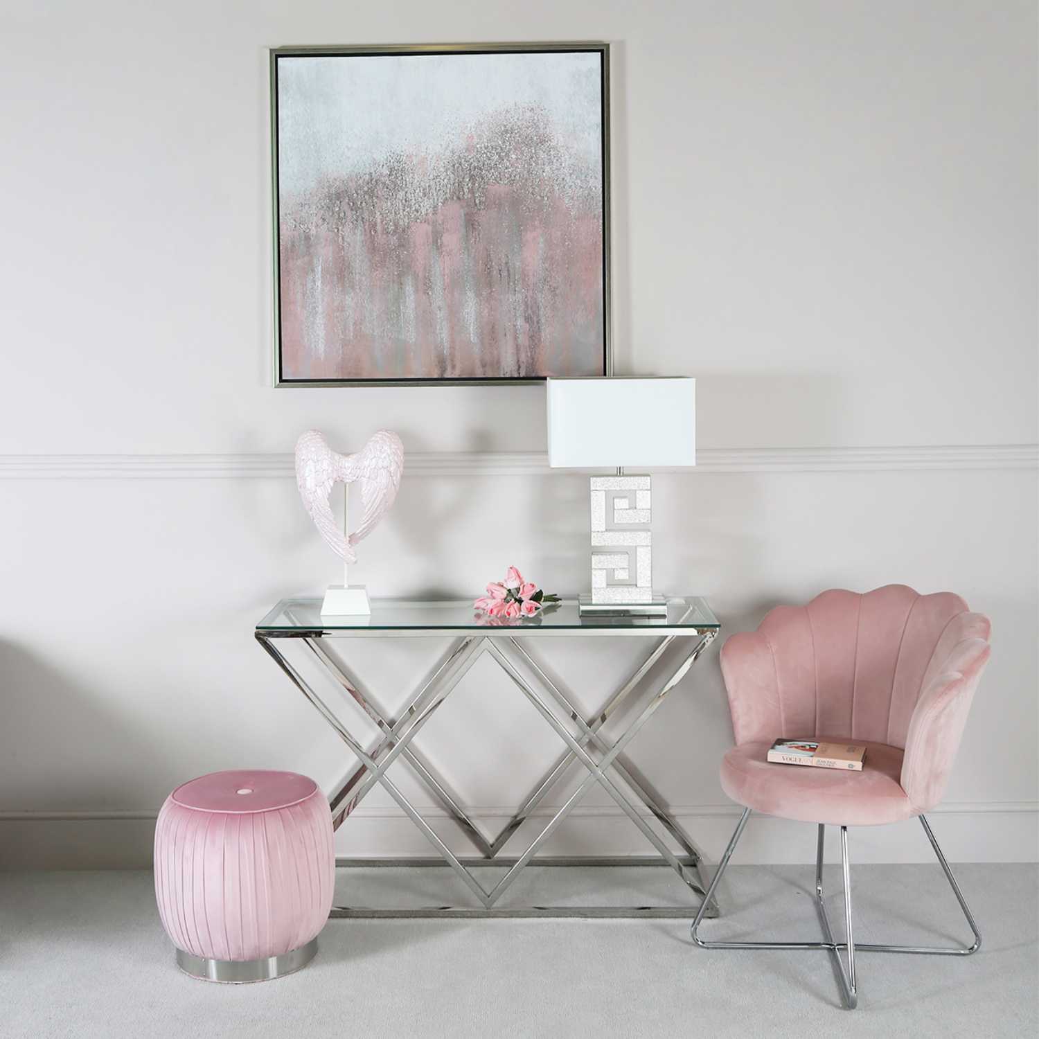 Mesa de vidro com estrutura metálica prateada e cadeira rosa em veludo