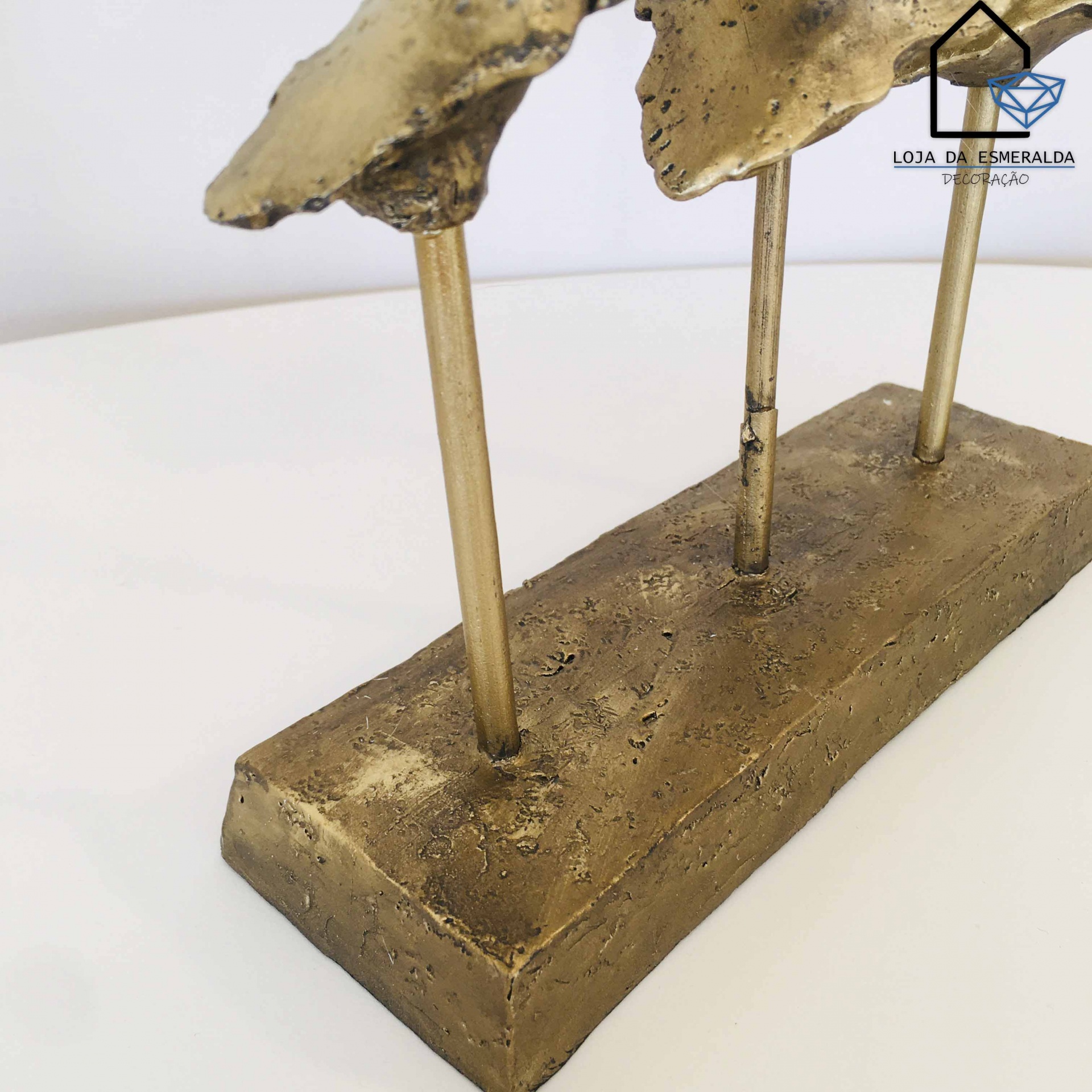 Base retangular de metal dourado com objetos verticais e logotipo Loja da Esmeralda