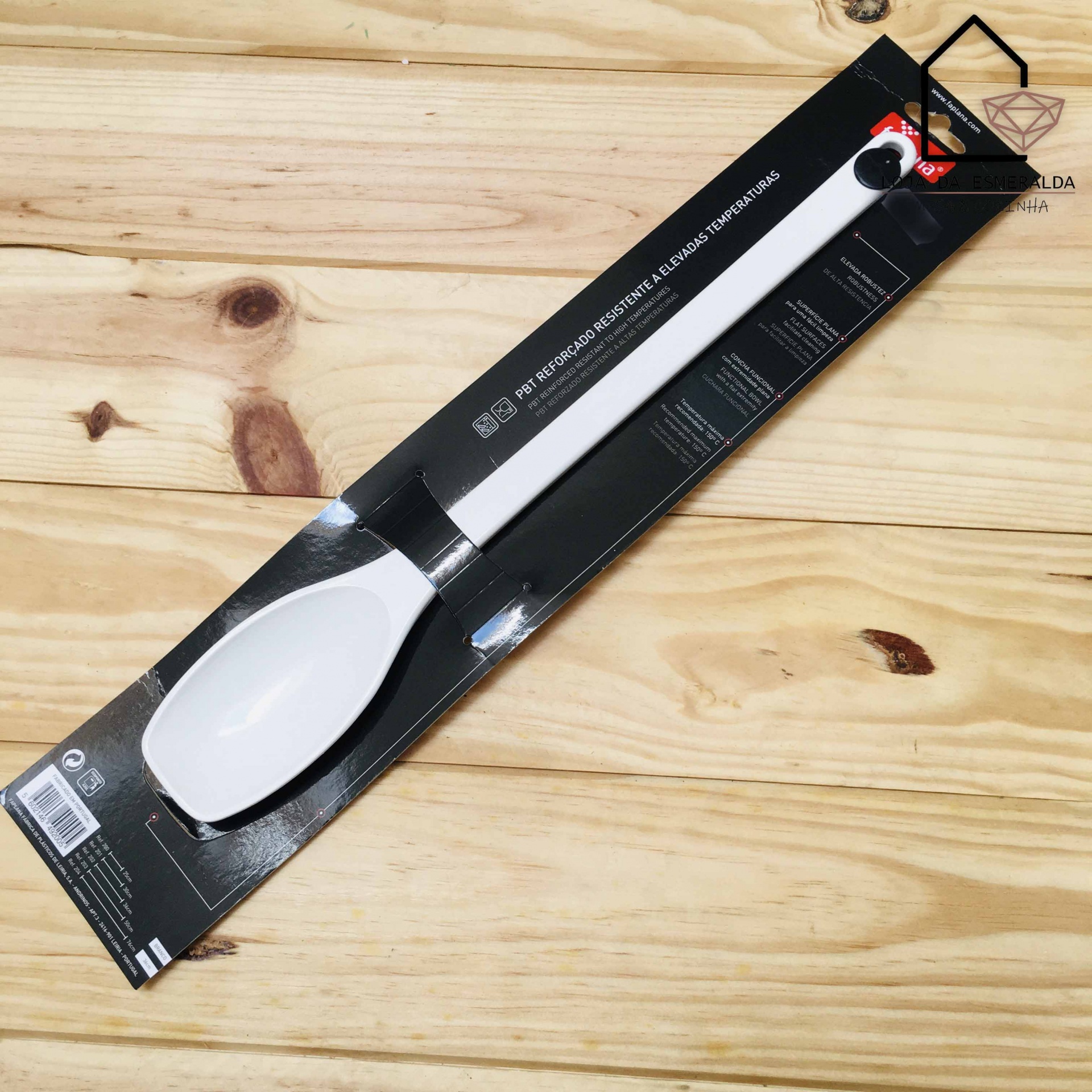 Colher de silicone branca com cabo comprido em embalagem preta sobre madeira clara