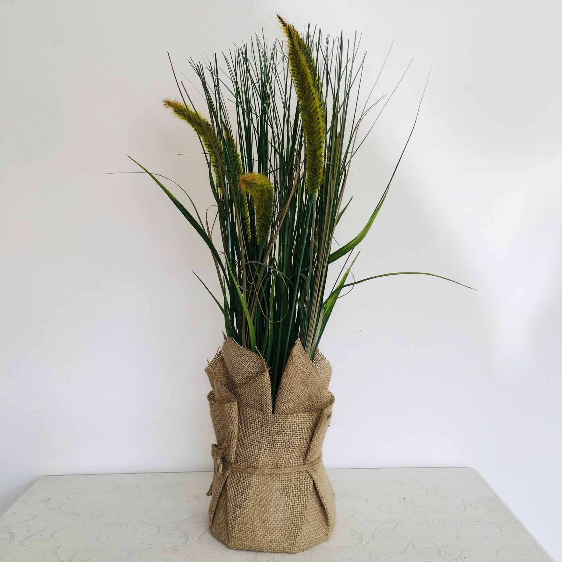 Arranjo de plantas com flores artificiais em vaso forrado de juta
