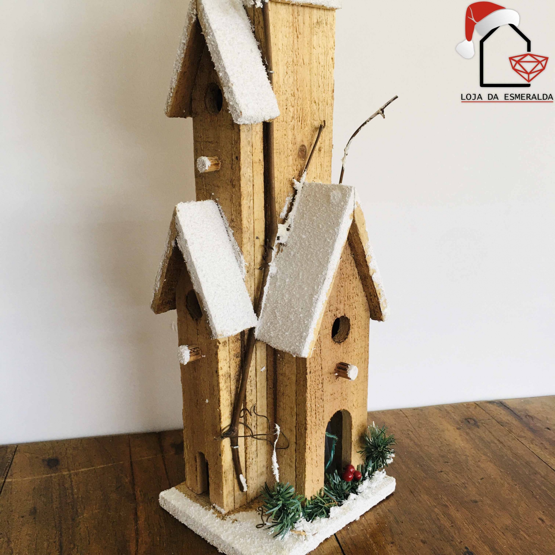 Casas decorativas de madeira com neve artificial e detalhes naturais sobre mesa de madeira