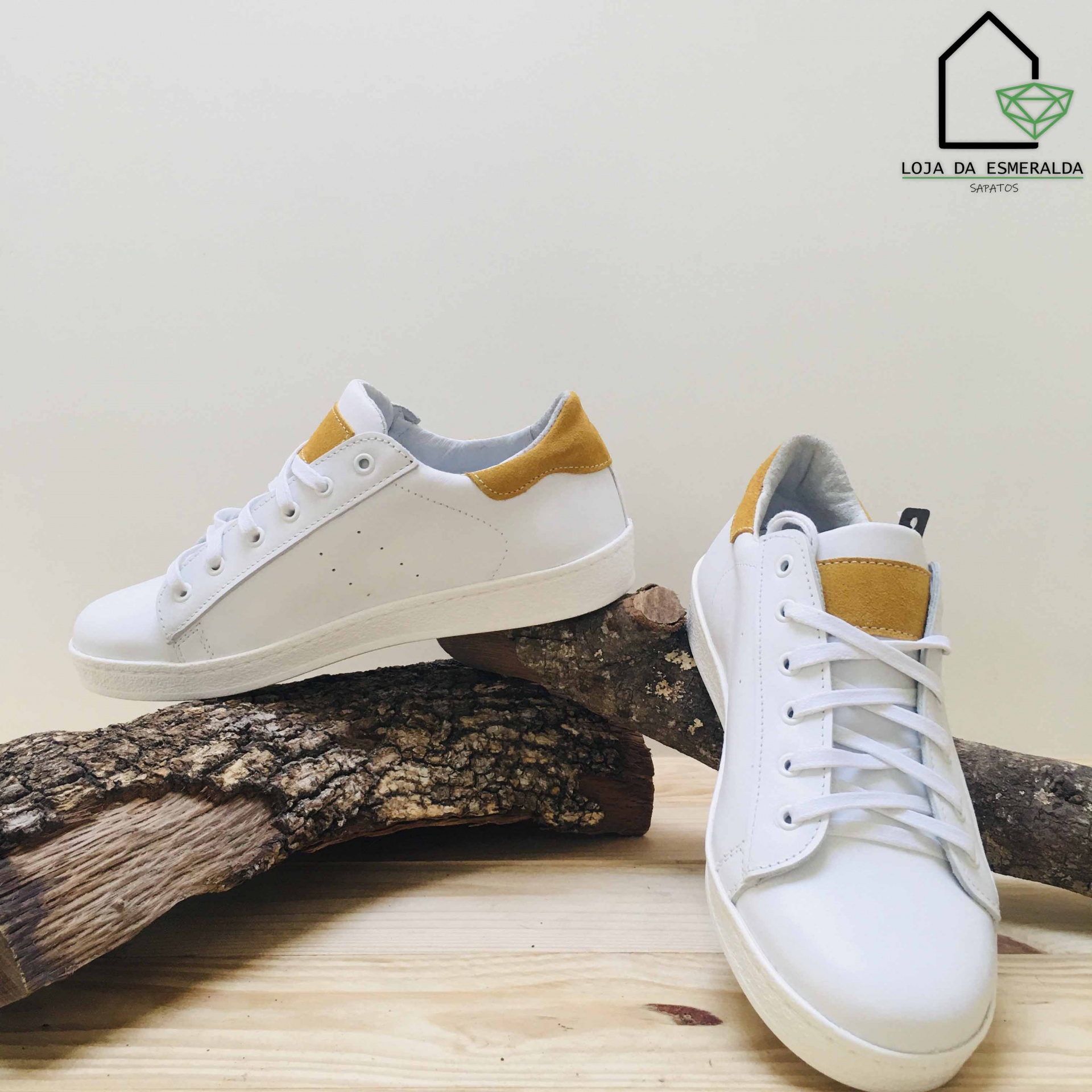 Par de sapatilhas brancas com detalhes castanhos sobre madeira
