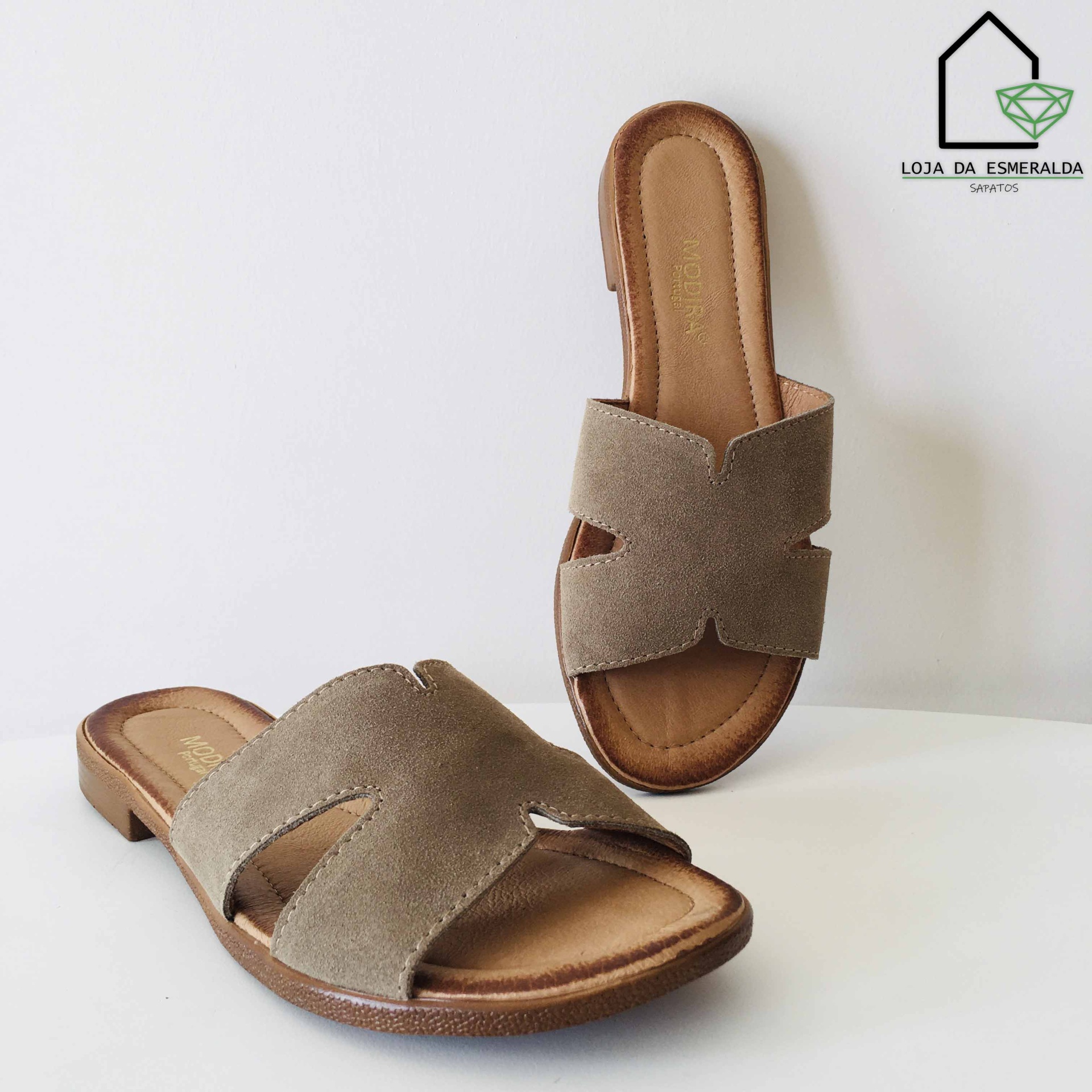 Sandálias tipo chinelo bege em camurça com sola castanha e logótipo da loja ao fundo