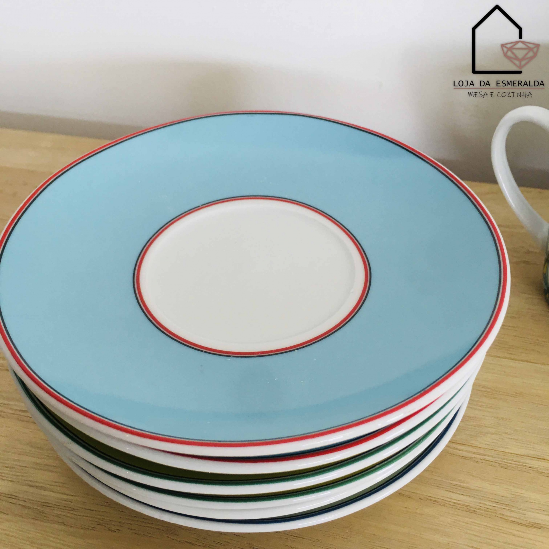 Seis pratos pequenos coloridos empilhados sobre mesa de madeira clara