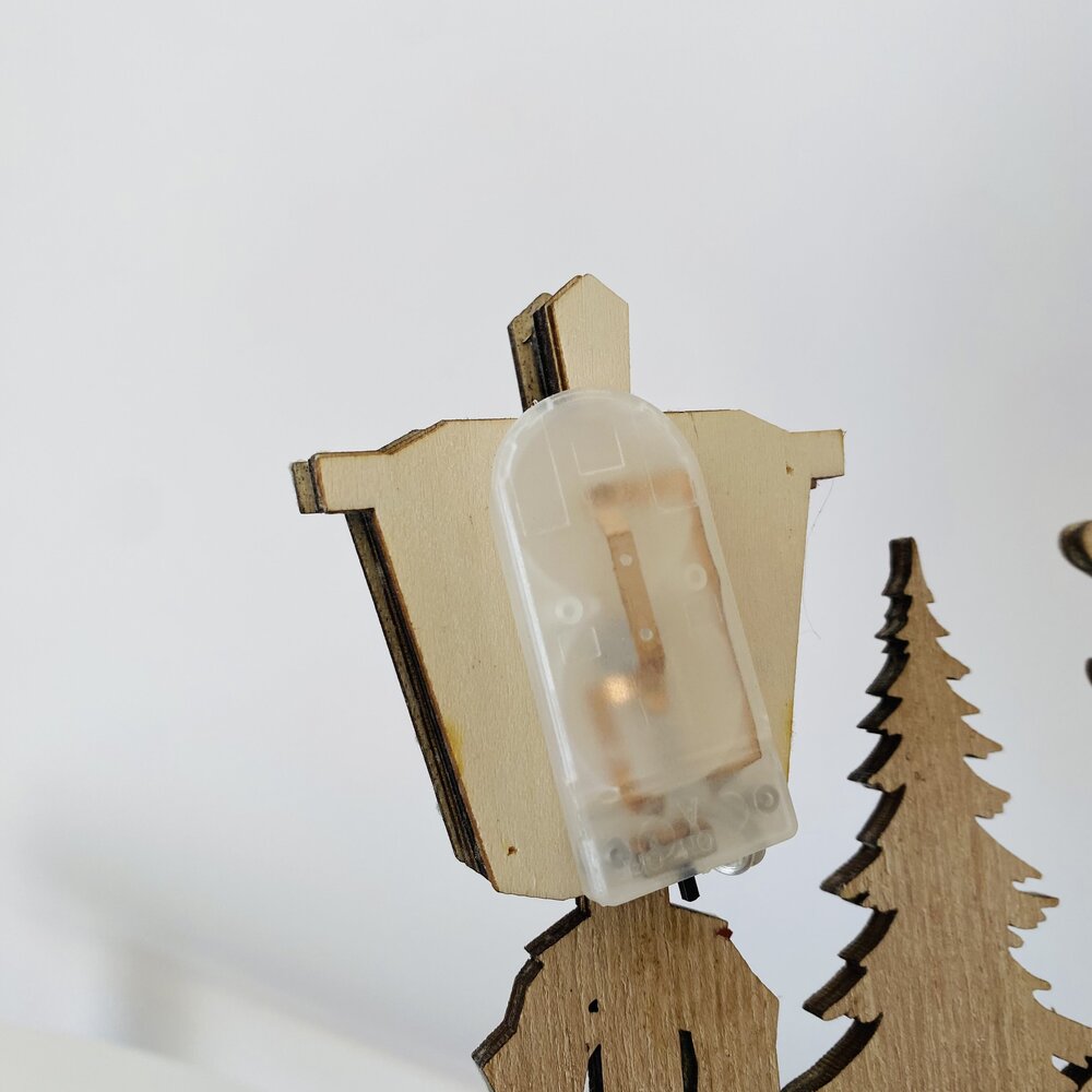 Silueta em madeira com suporte de plástico e árvore de Natal em madeira ao lado