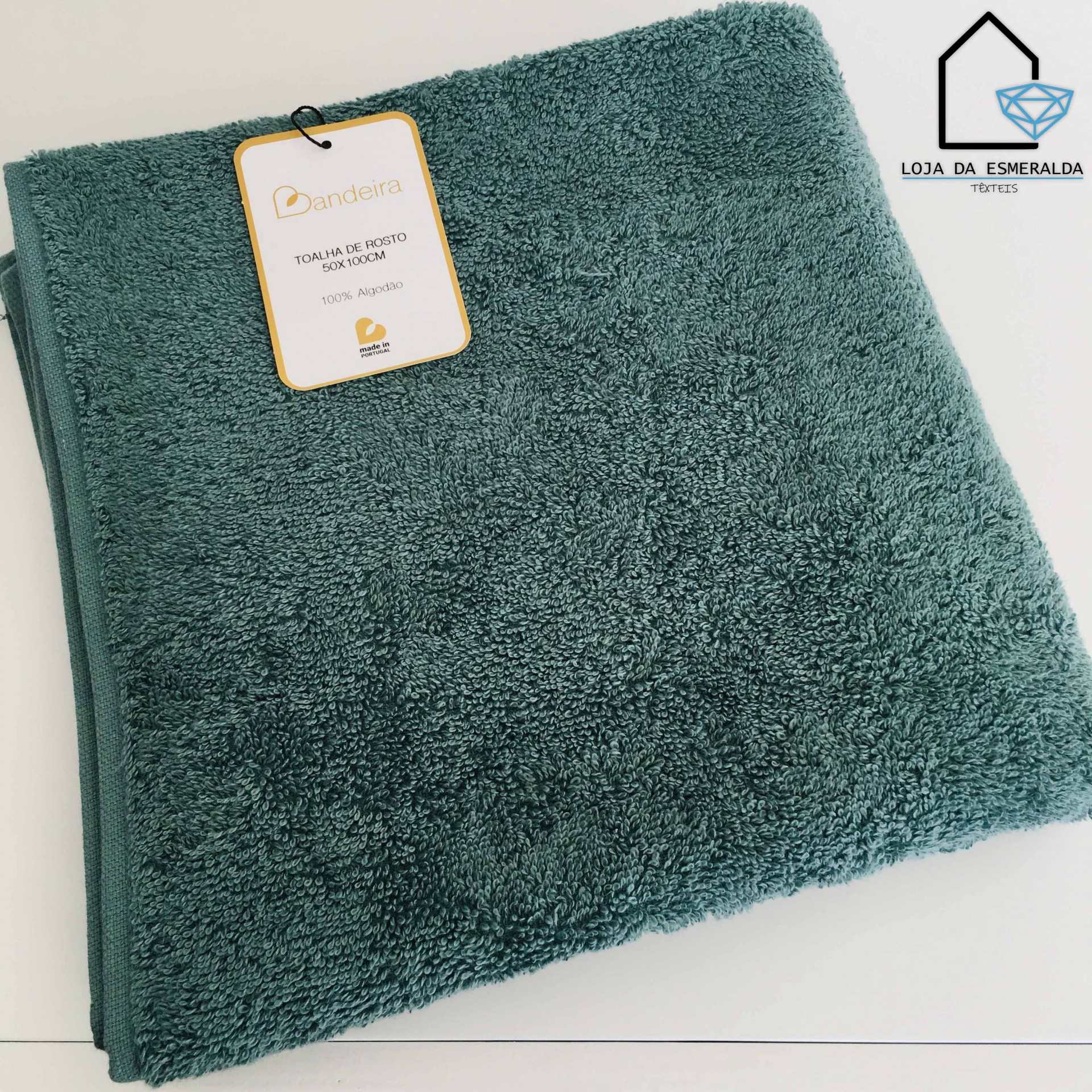 Toalha de rosto verde escuro com etiqueta da marca Bandeira e logótipo da Loja da Esmeralda Têxteis