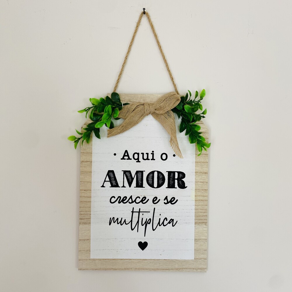 Placa decorativa com texto e folhas verdes pendurada na parede