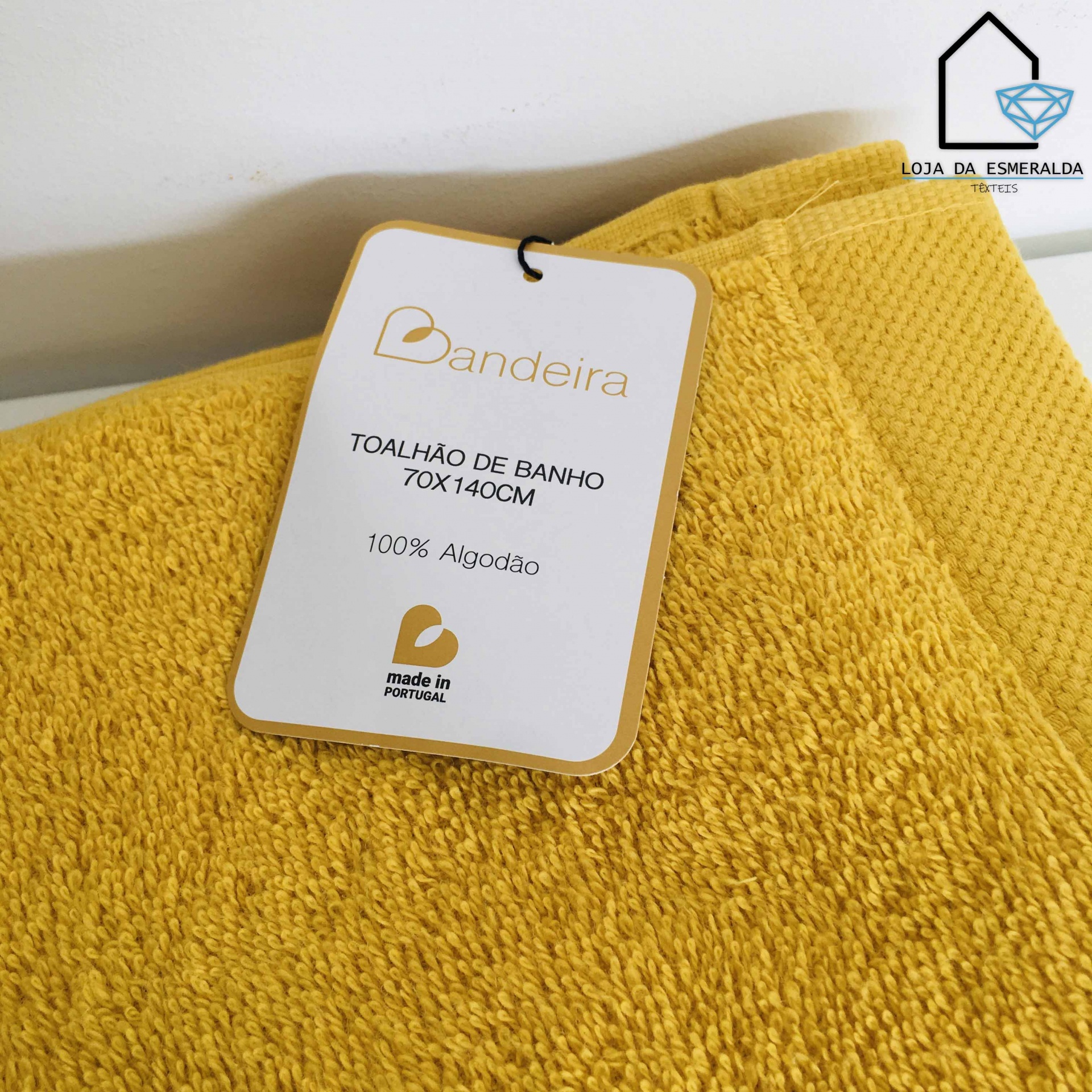Toalhão de banho amarelo mostarda com etiqueta branca da marca Bandeira