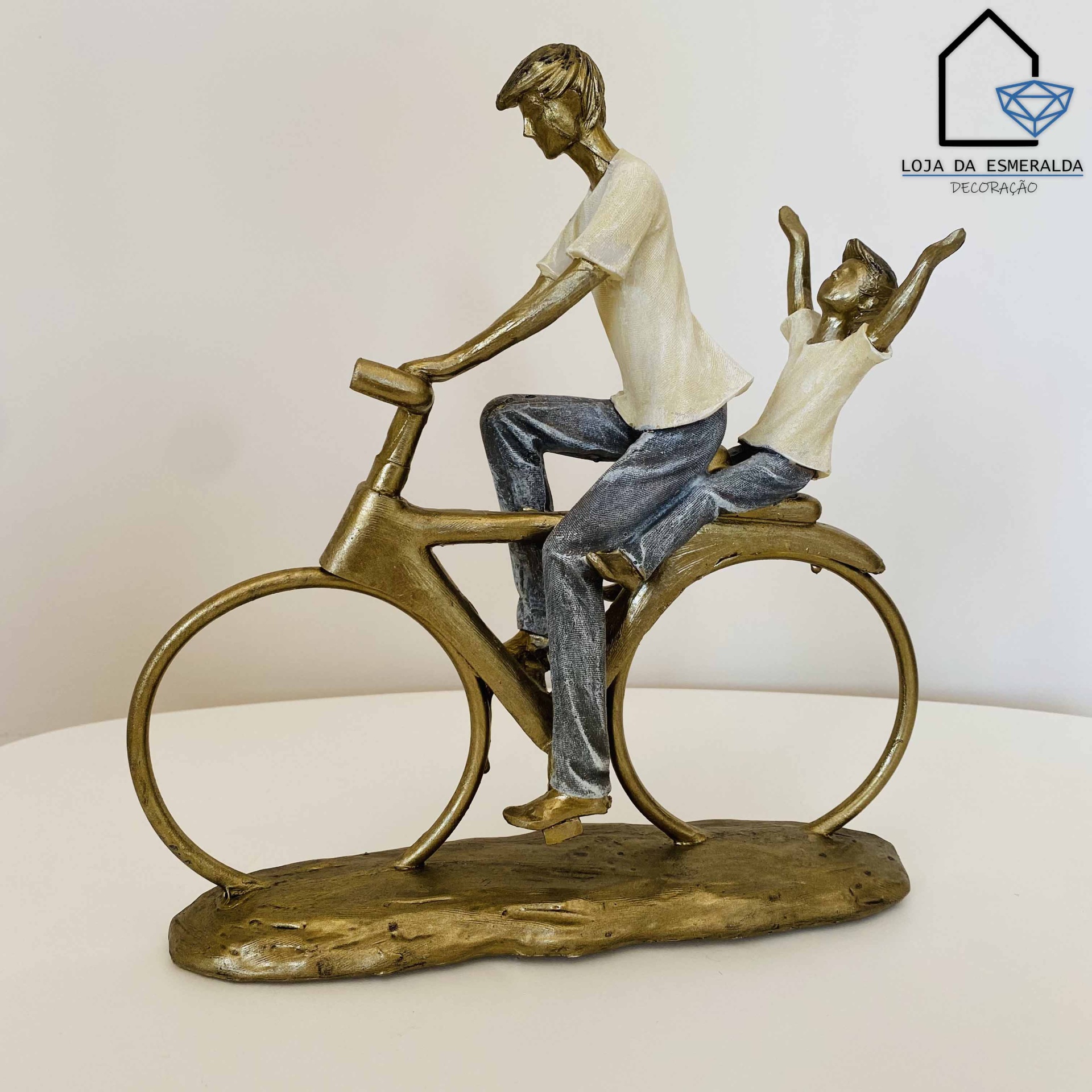 Estátua decorativa de duas figuras humanas numa bicicleta com logótipo da loja ao fundo