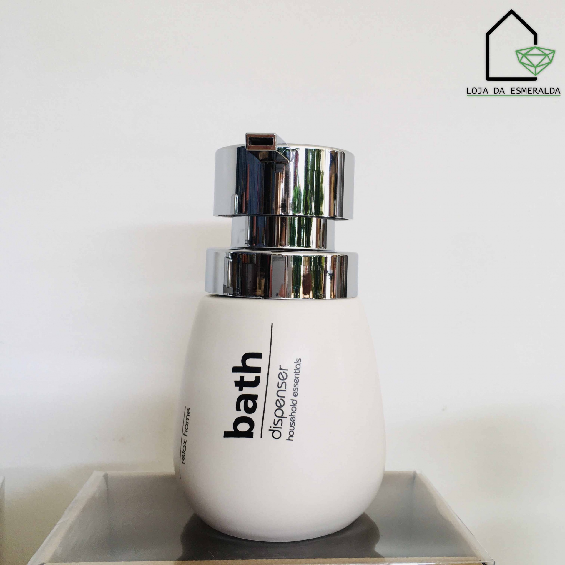 Dispenser de banho branco com tampa metálica prateada, texto 'bath dispenser for soap or lotion' e logótipo LOJA DA ESMERALDA ao fundo