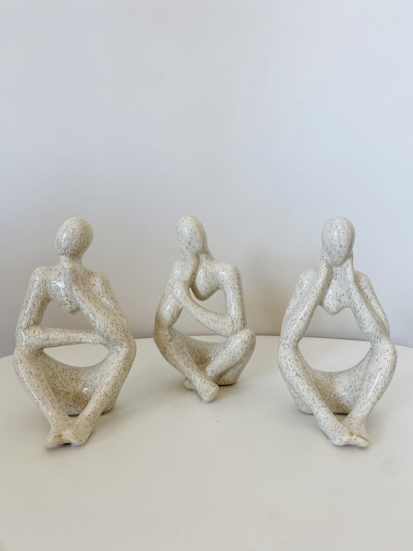 Três esculturas cerâmicas abstratas de figuras humanas sentadas