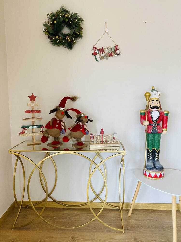 Decoração de Natal com renas de pelúcia numa mesa dourada e soldado de pau ao lado