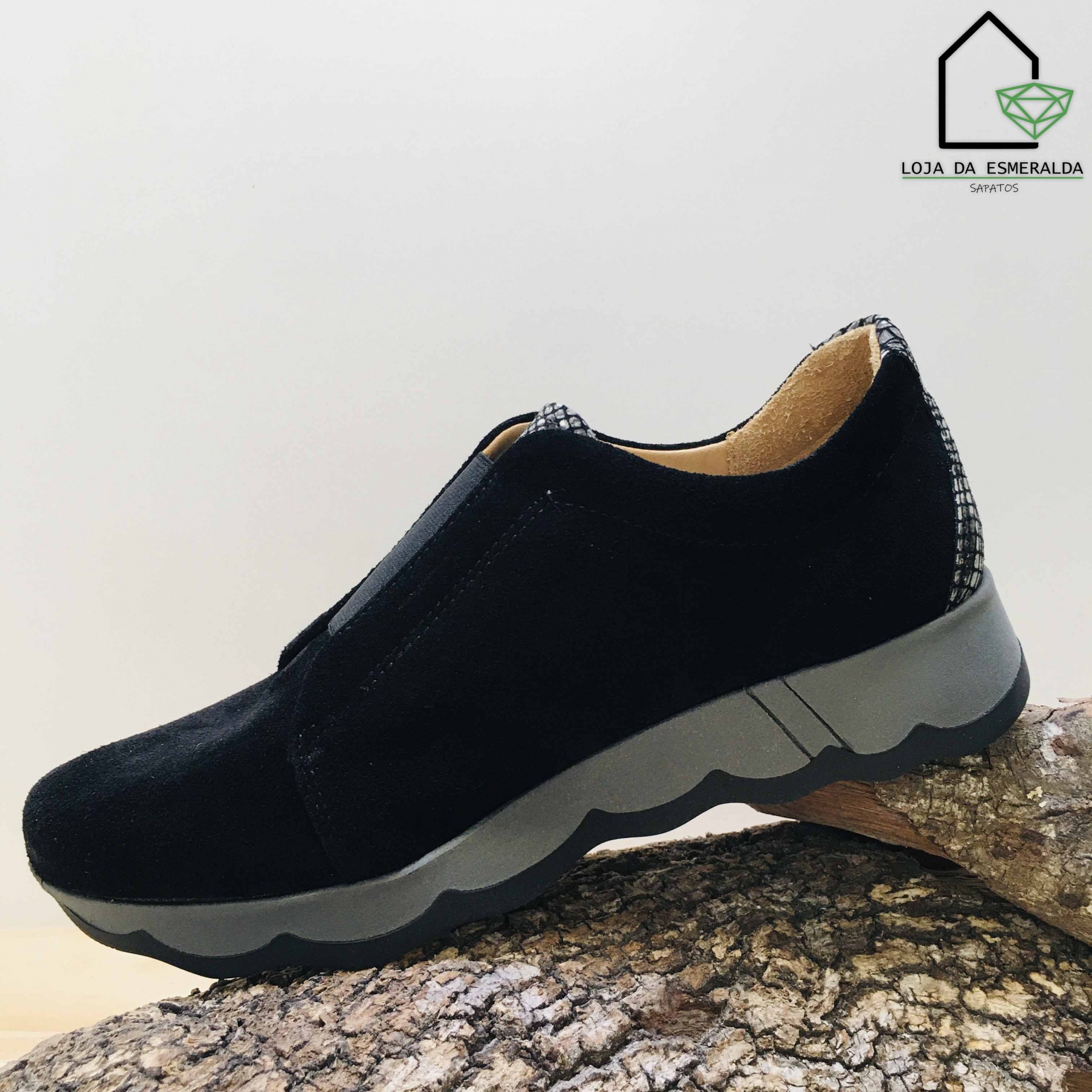 Ténis pretos em material de camurça com sola cinza e detalhe no calcanhar