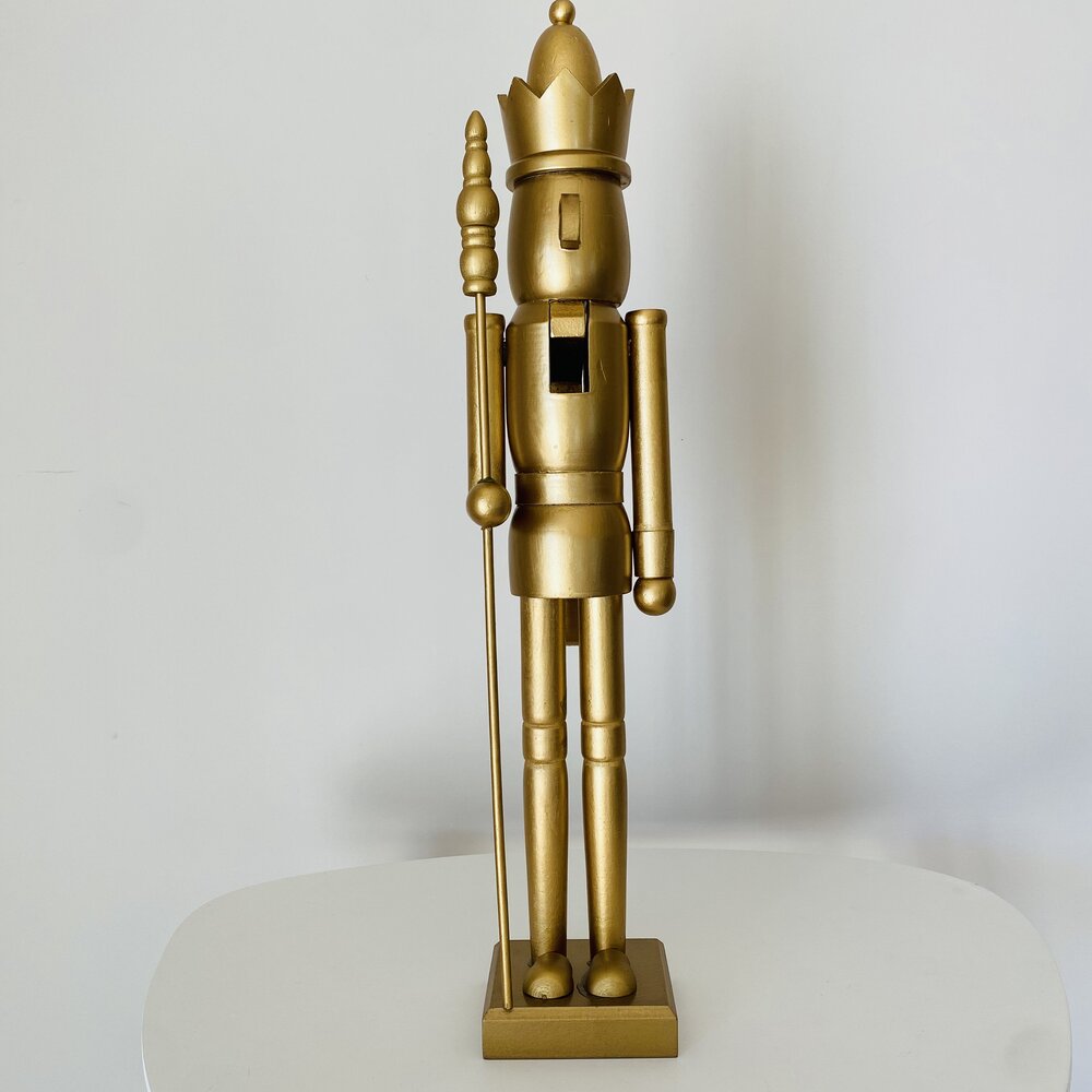Boneco soldado dourado com cetro sobre base quadrada, fundo branco