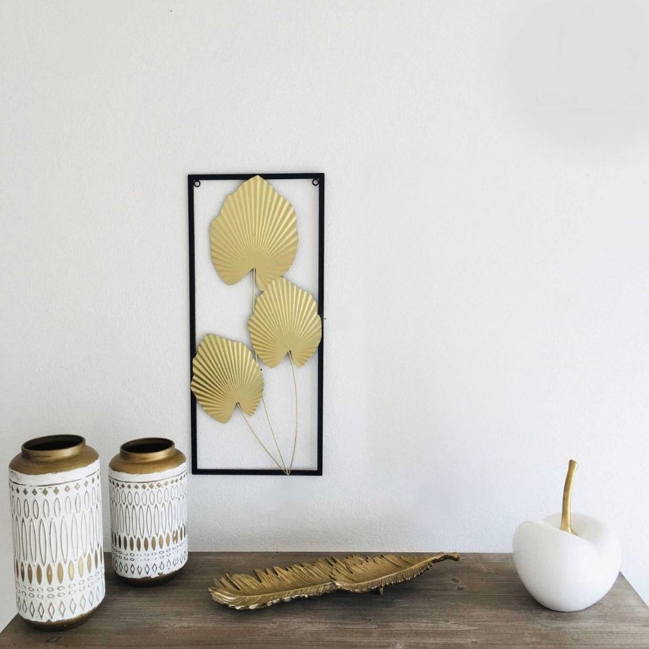 Artigos decorativos dourados e brancos sobre mesa de madeira com decoração de parede